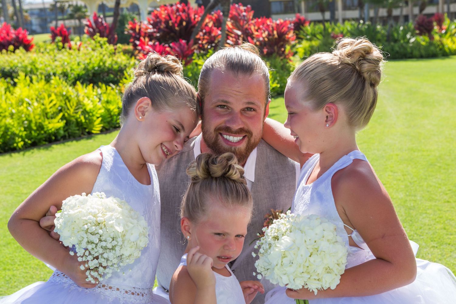 Cheerful wedding party photo in sunny garden with white bouquets in a wedding at Princeville in Kauai..