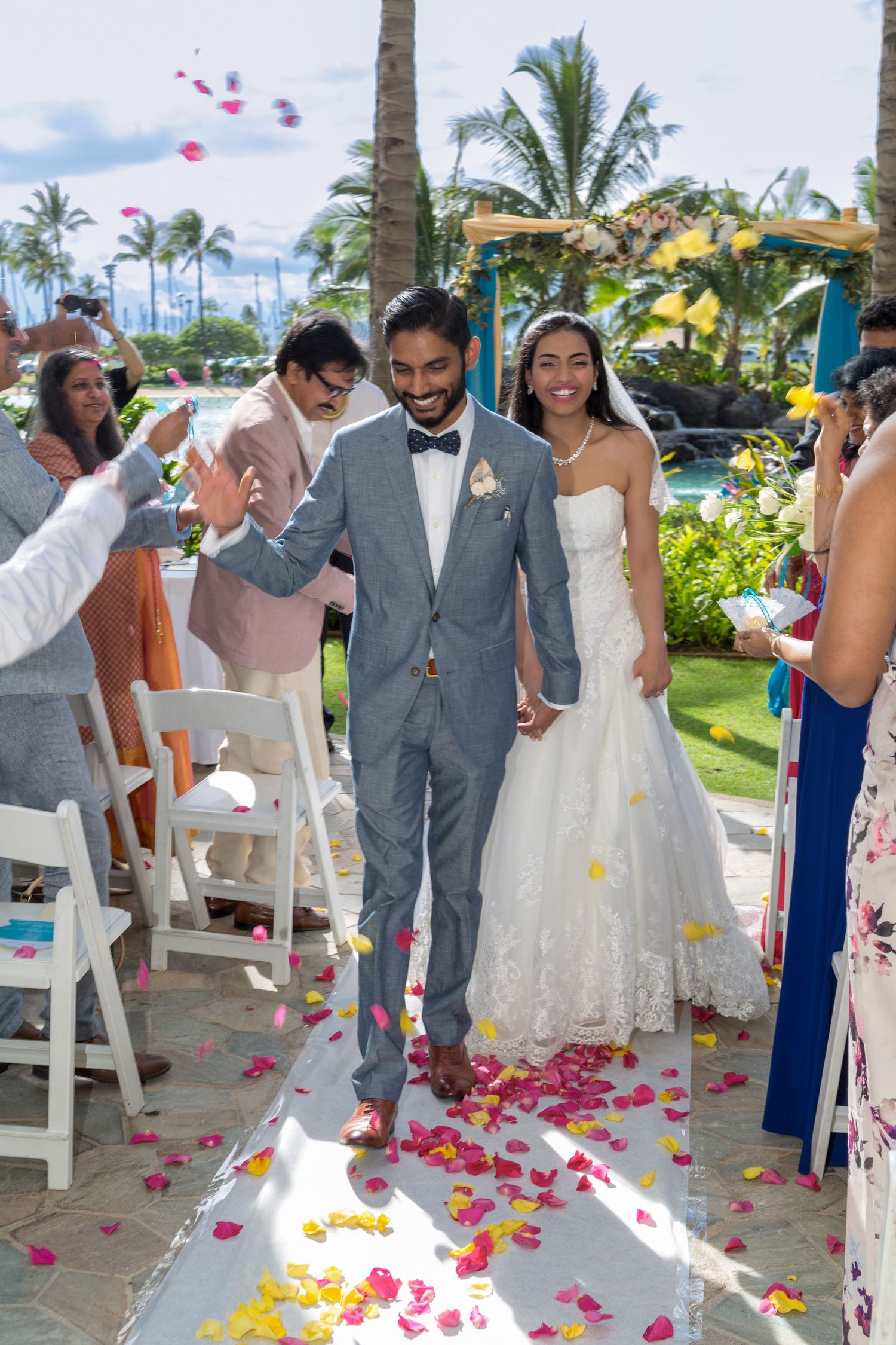 Wedding celebration with flower petals being tossed as the couple walks down the aisle at the Hilton Waikoloa Village hotel in Honolulu.