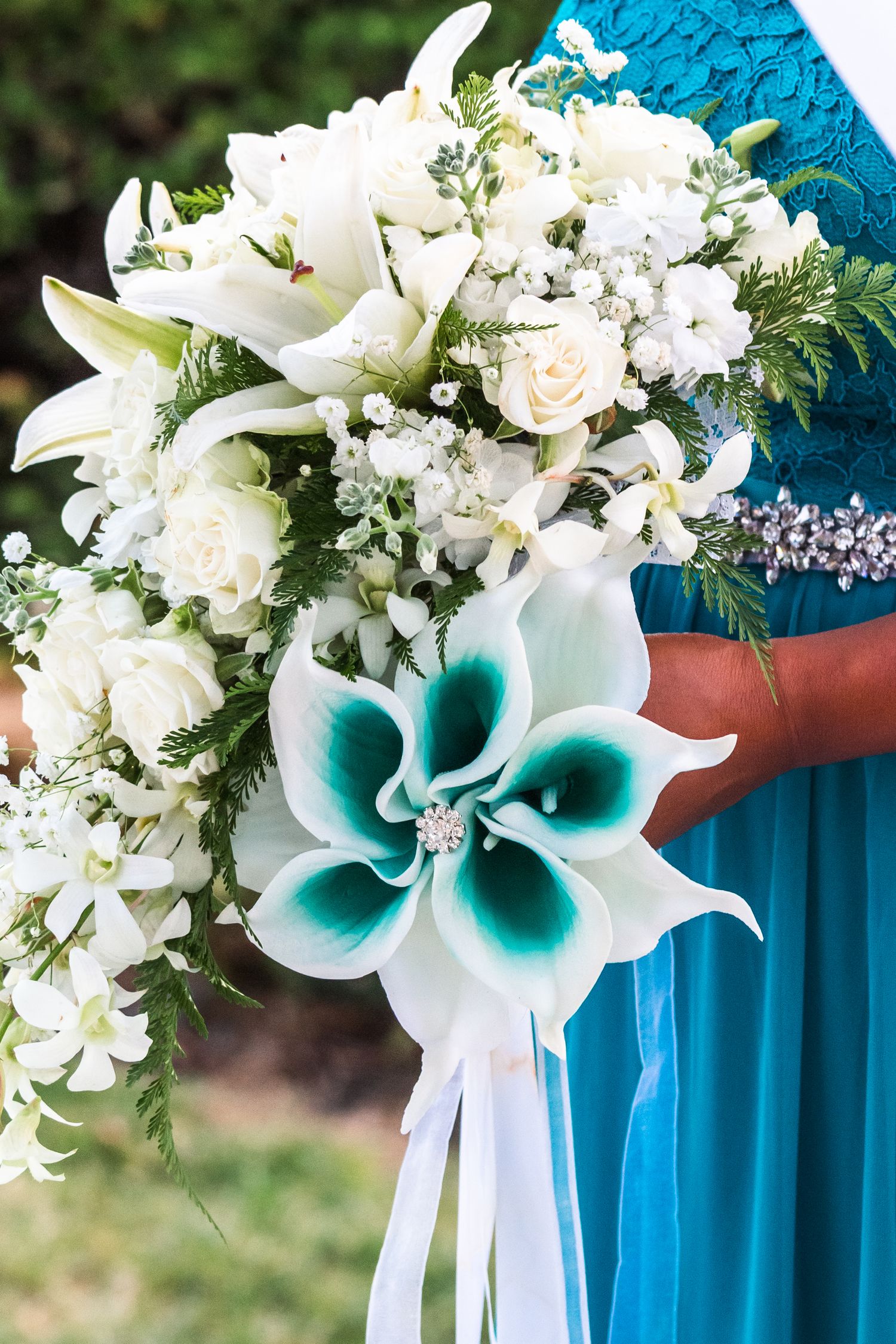 White lily and rose bouquet with teal calla lilies against turquoise bridesmaid dress.