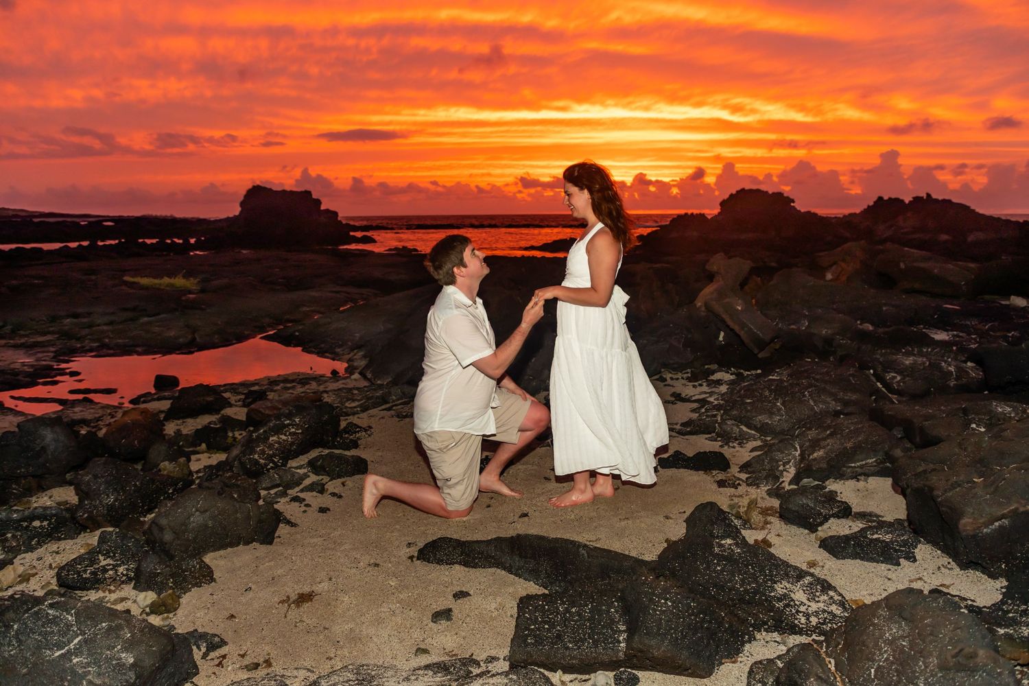 A romantic proposal on volcanic rocks during a vibrant Hawaiian sunset at the Old Airport Beach Park in Kailua Kona, Hawaii.