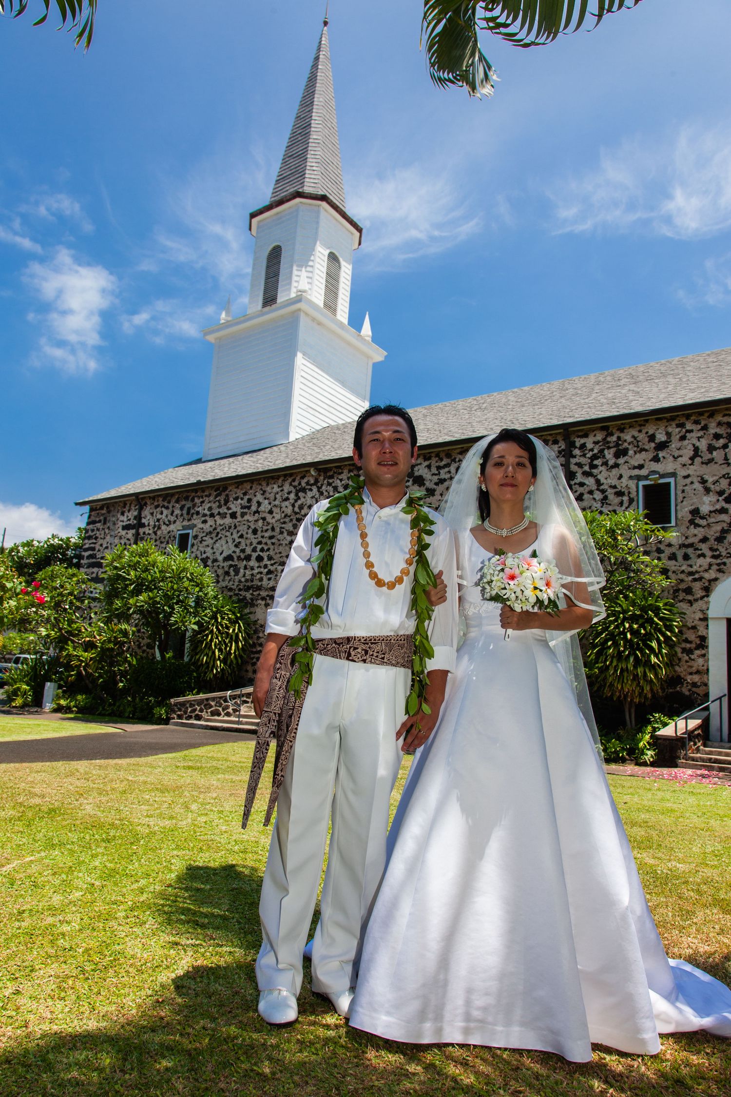 Traditional Hawaiian wedding couple standing in front of the Mokuaikaua church in Kailua Kona downtown.