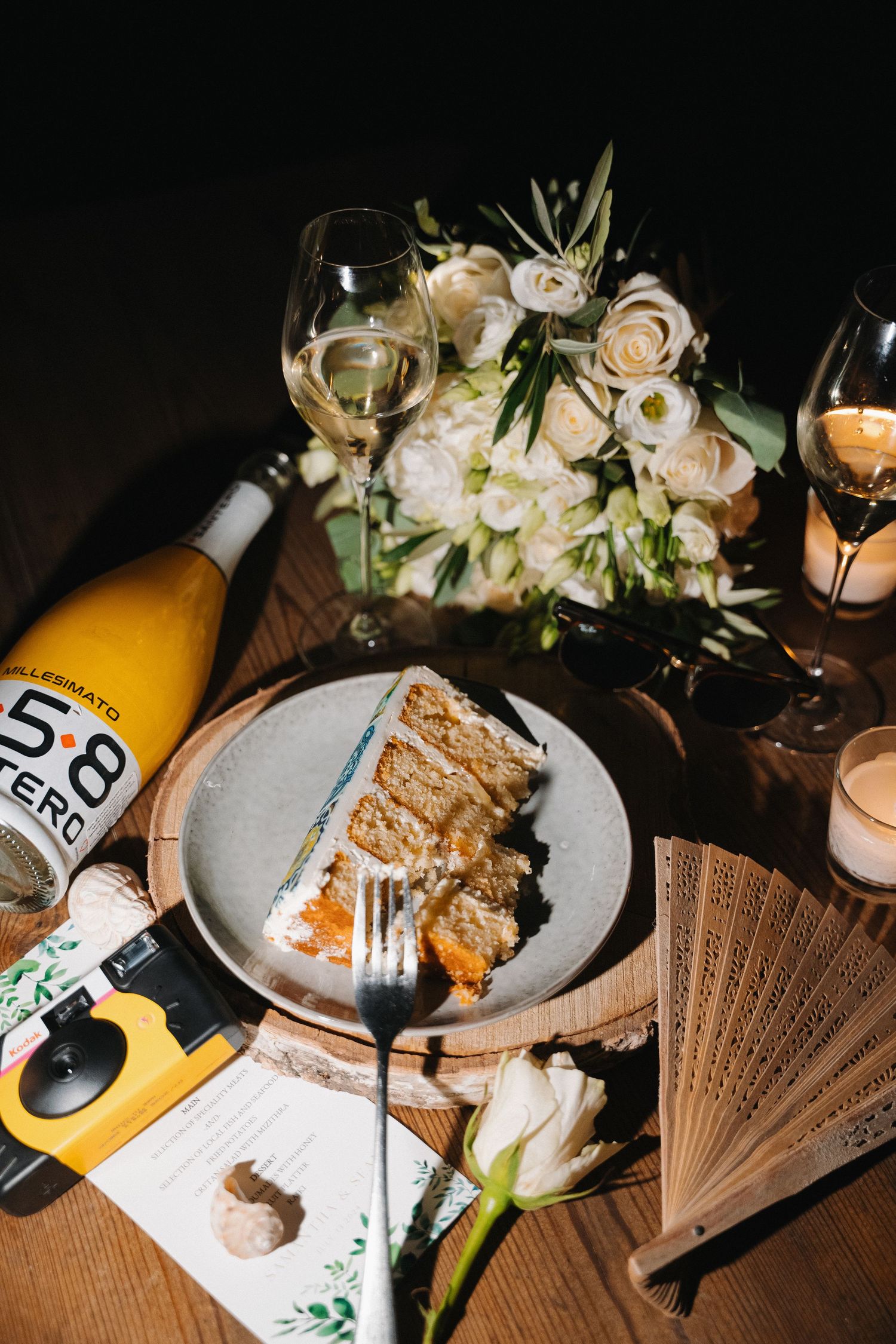 An elegant table setting at night with lit candles, flower arrangements, wine bottles and plates of food in a sequence.