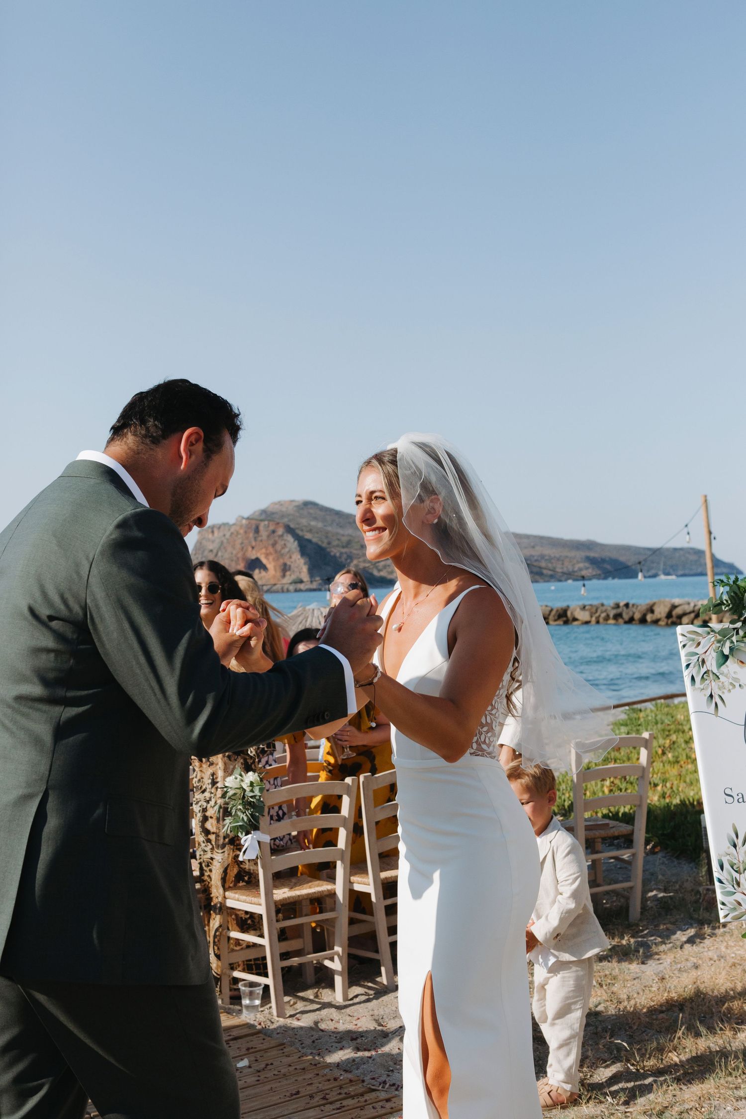 Couple exchanges rings during oceanside wedding ceremony with scenic coastal backdrop.