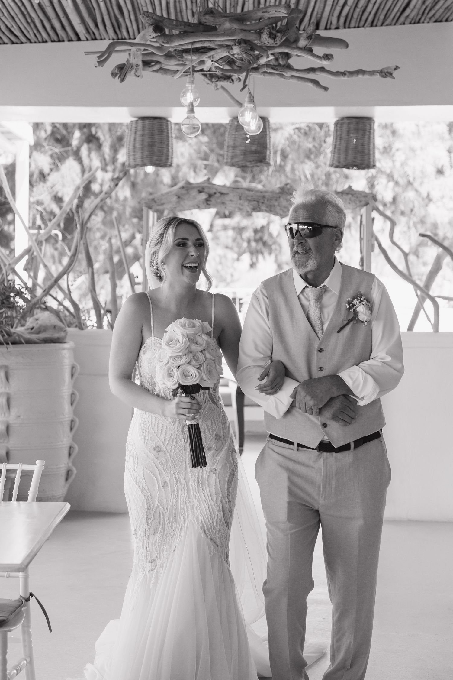 Dancing couple in wedding attire share intimate moments on a bright covered patio during their celebration.