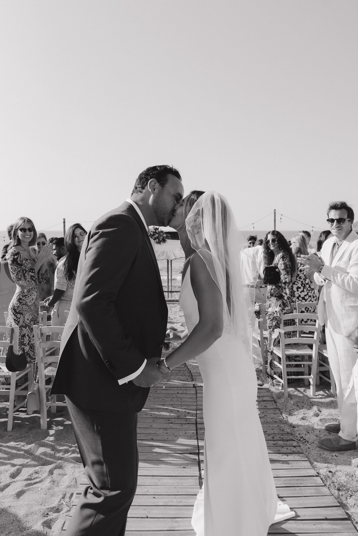 Romantic wedding moment captured in black and white on a beachfront deck.