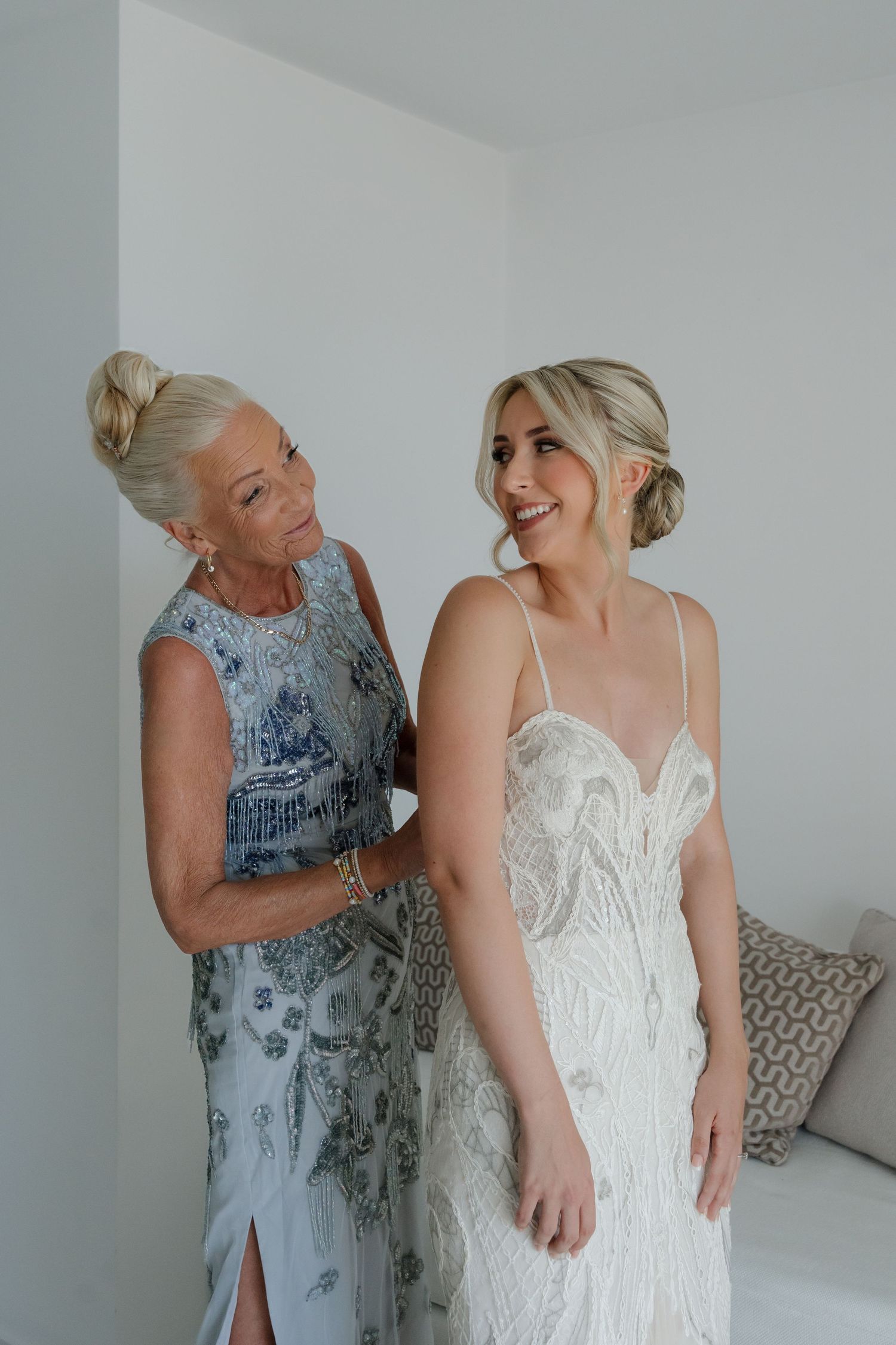 Elegant wedding scene with bride in lace gown sharing tender moment during preparations.