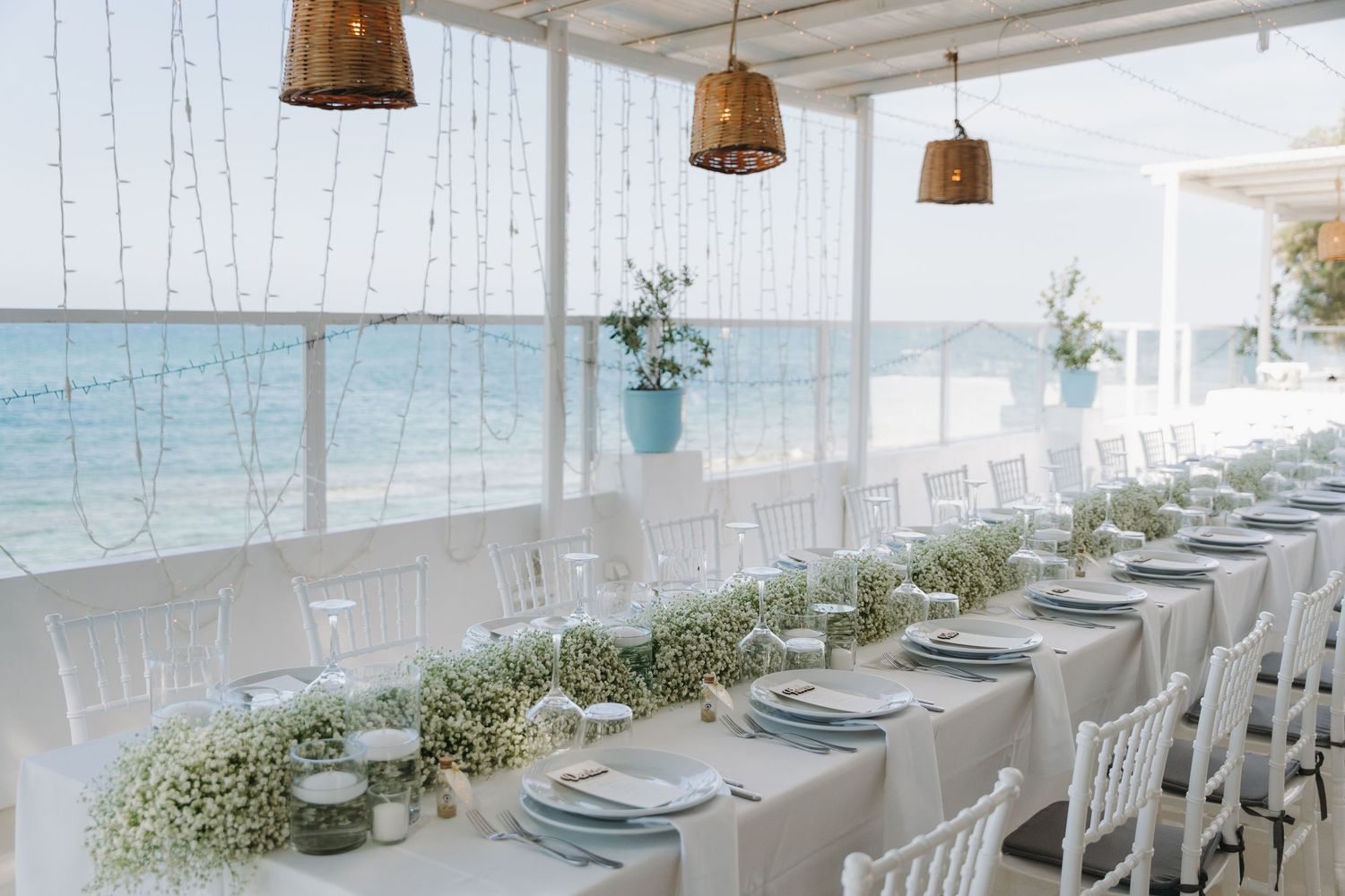 Elegant beachside wedding reception setup with white chairs and floral table runners.