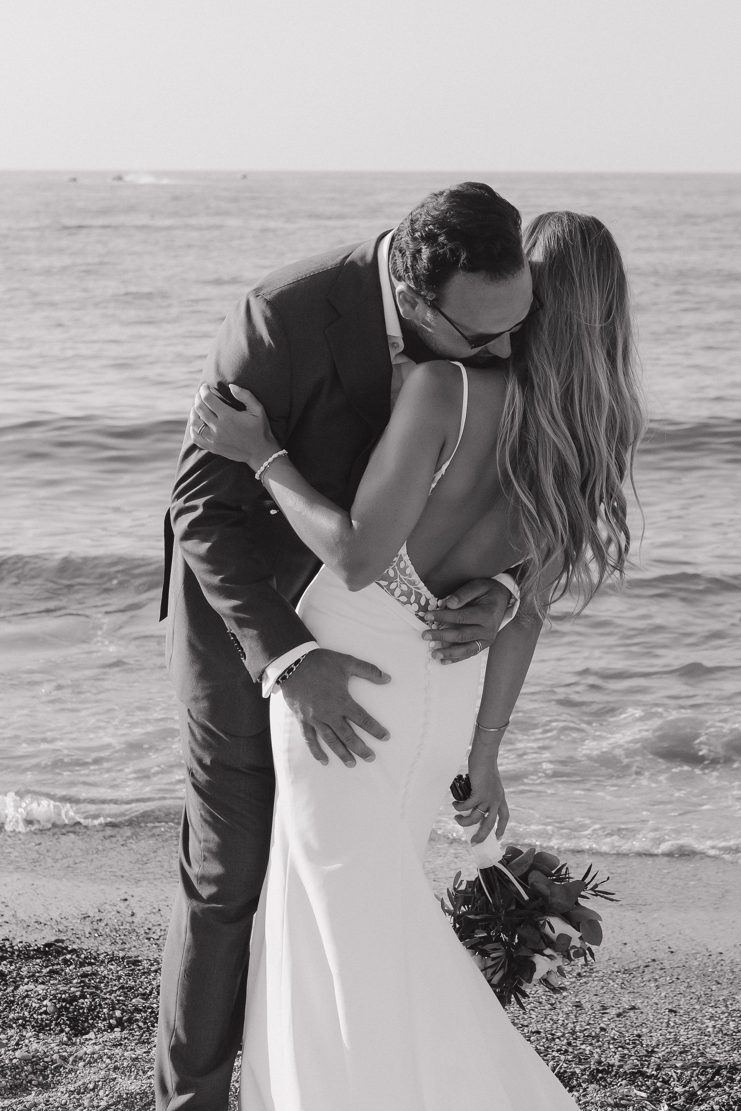 Black and white romantic beach wedding portrait of couple embracing.