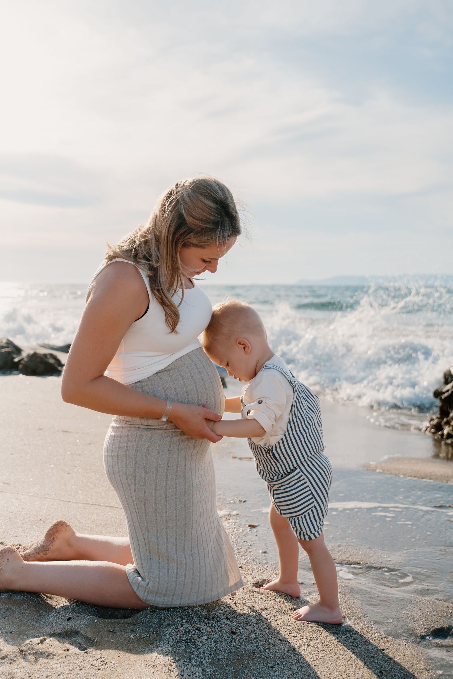 Parent and toddler playing together by the ocean waves.