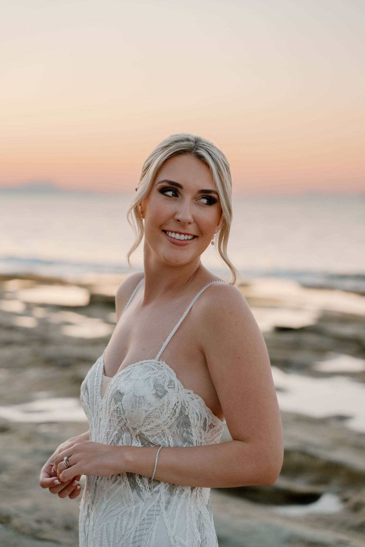 Beautiful beachside bridal portrait at sunset with coastal rocks and ocean in background.