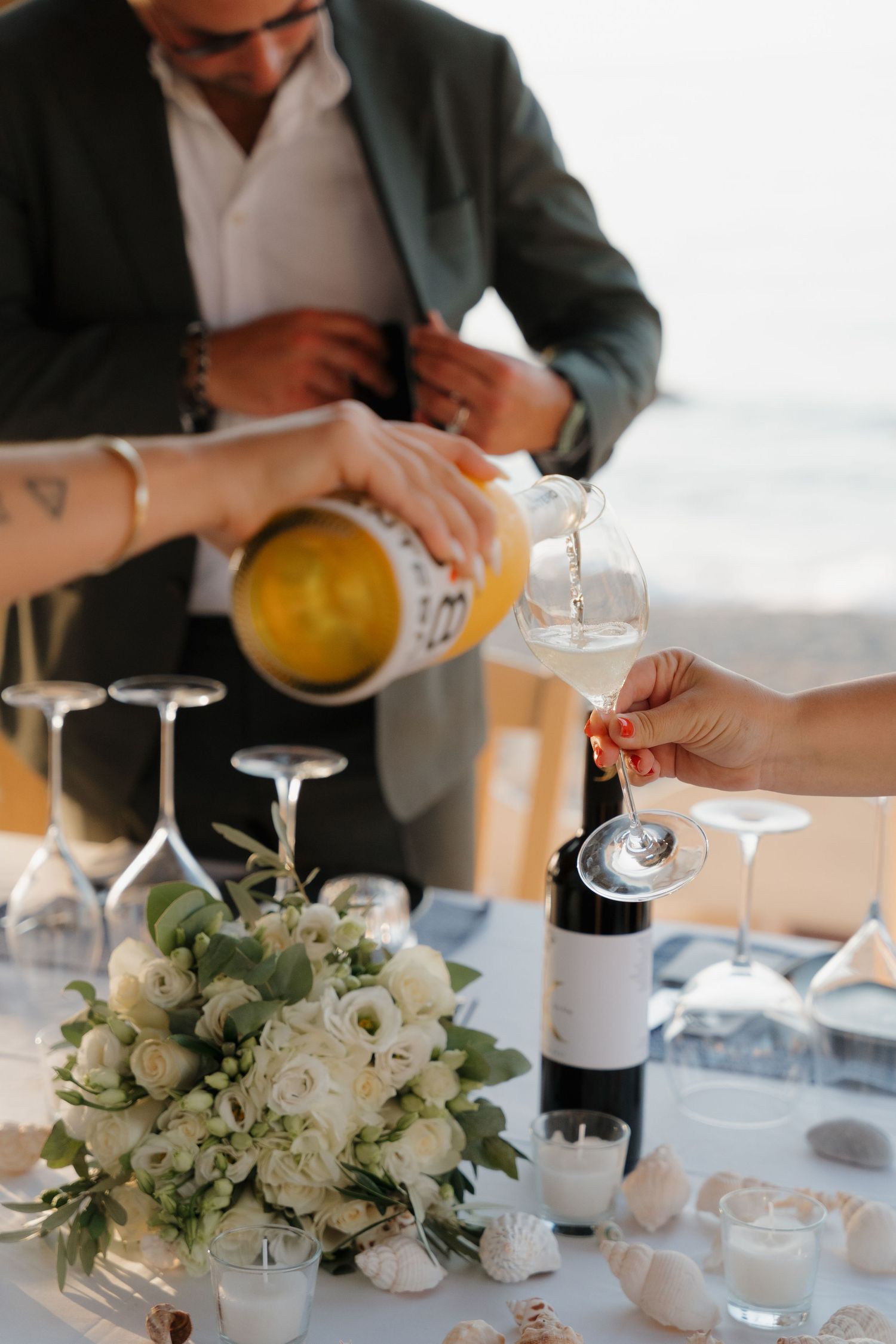 Wedding table setup with white floral centerpiece as champagne is being poured into glasses.