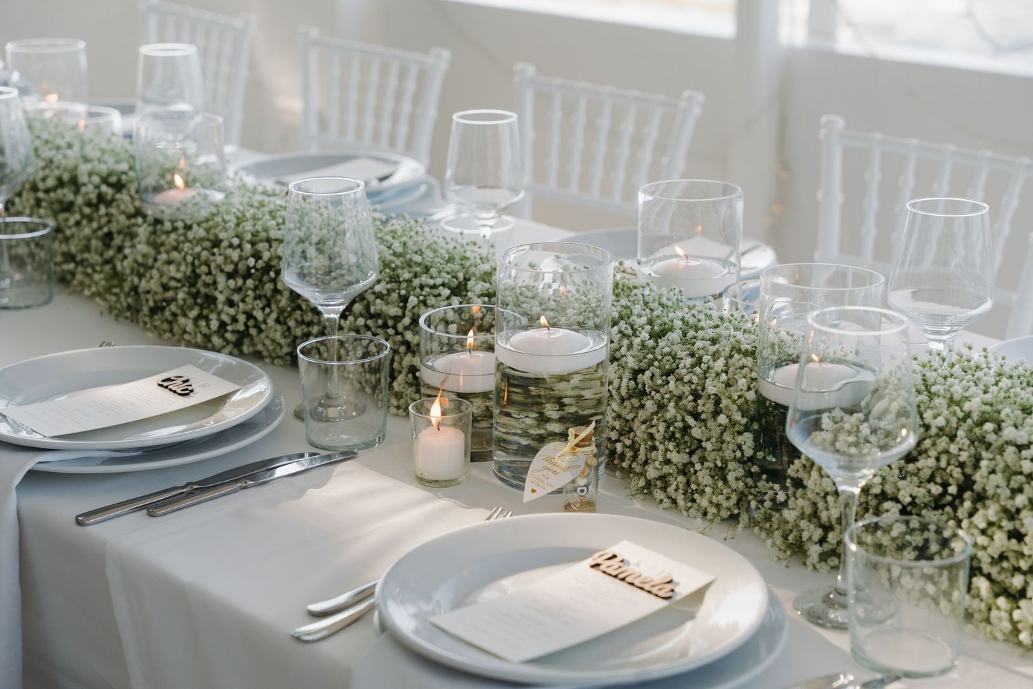 Elegant wedding table setting with baby's breath centerpieces and crystal glassware.