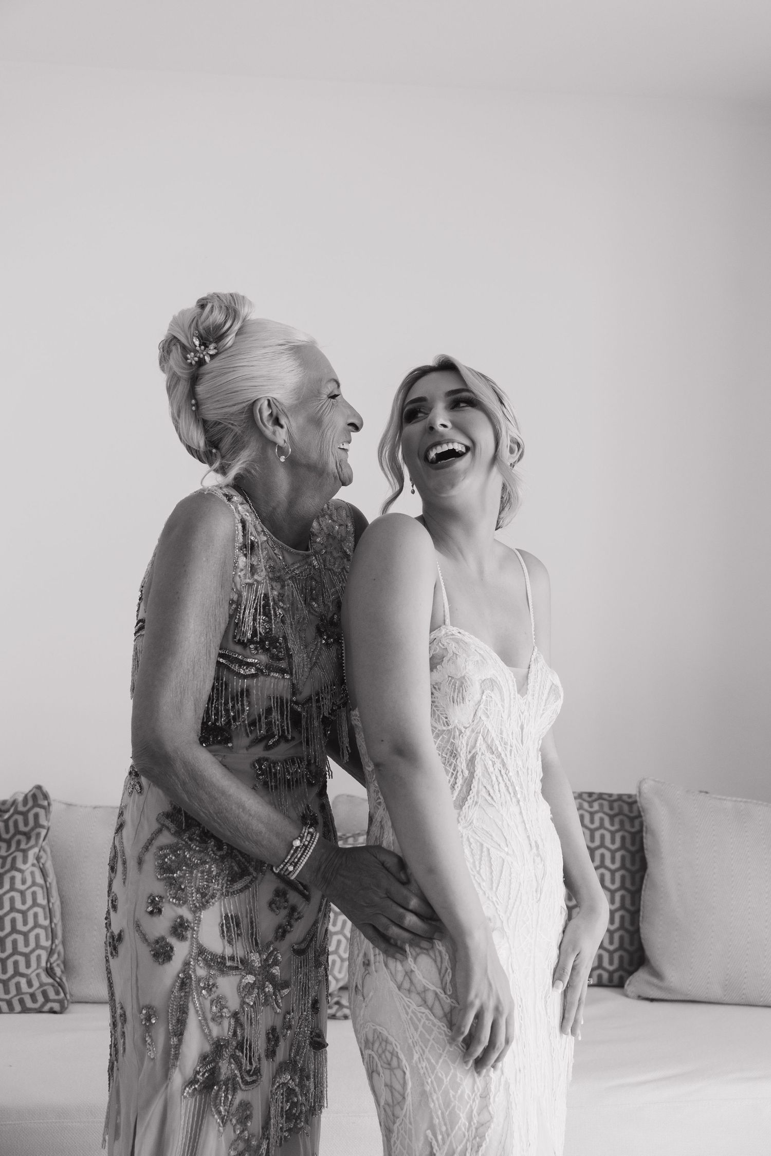 Two women sharing a candid laughing moment in formal attire.