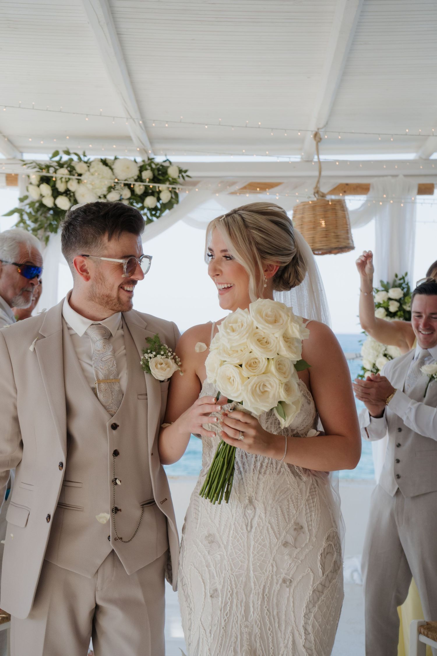 Wedding celebration in bright white venue decorated with hanging baskets and floral arrangements.