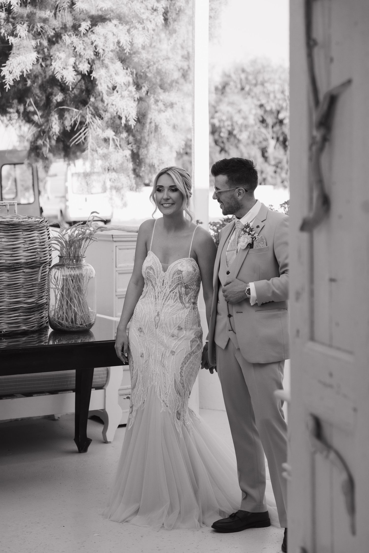 A couple poses in formal attire during their seaside wedding with wicker decor.