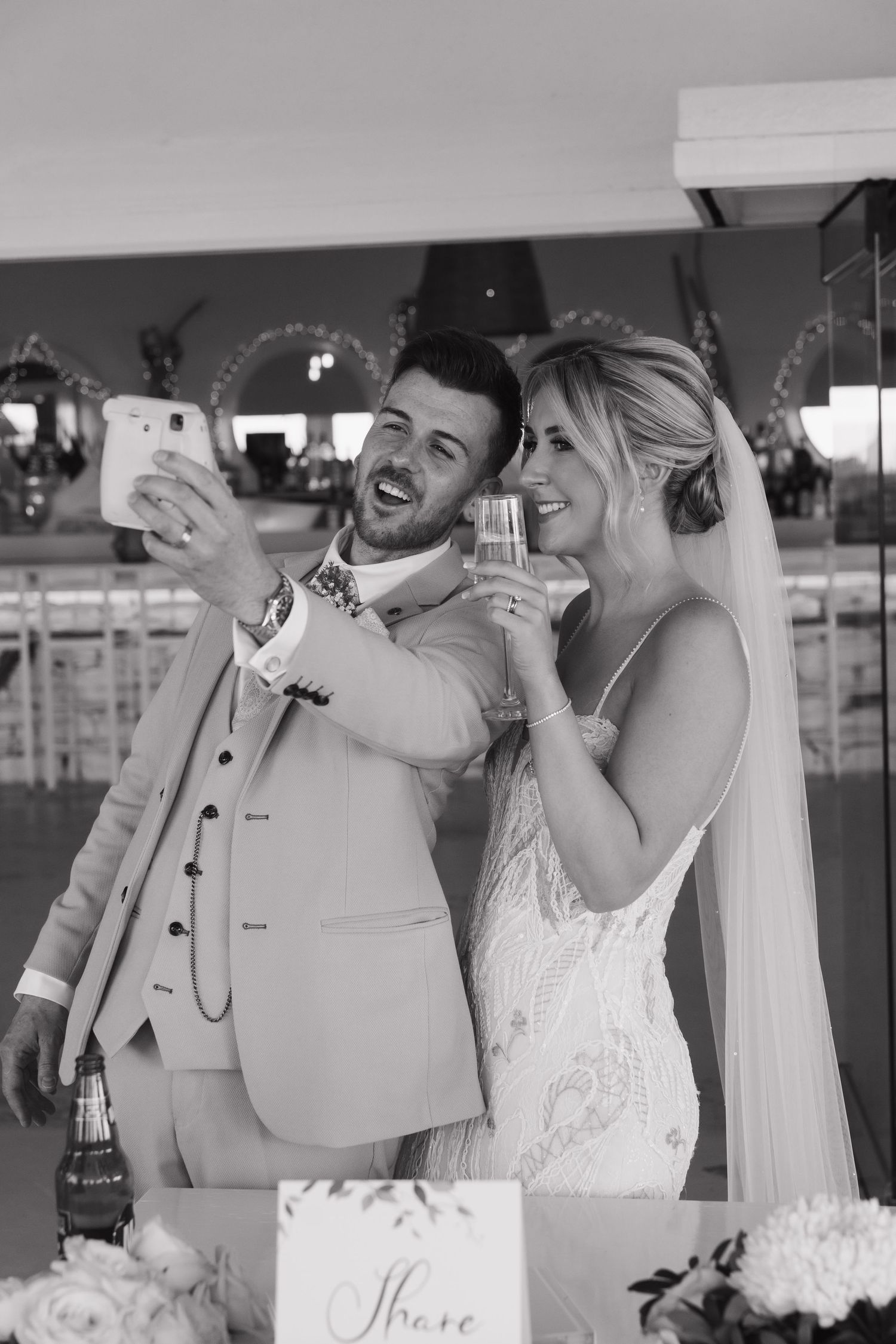 A couple laughs while taking selfies during their wedding reception.