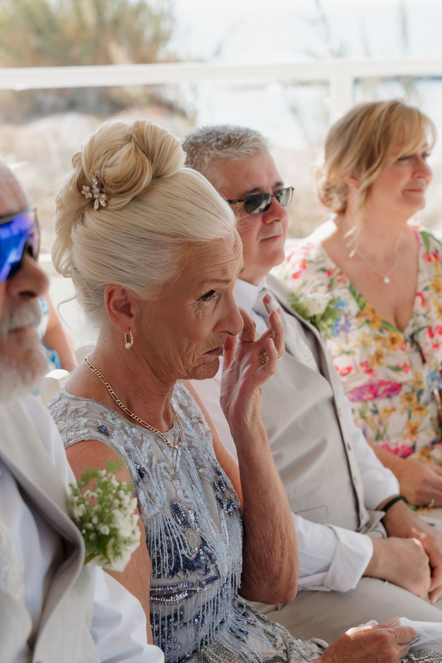 A candid moment at a wedding reception showing guests dressed in summer attire sitting together.
