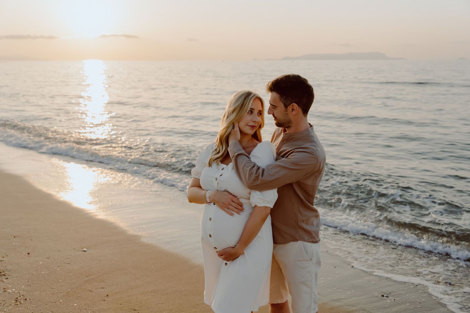 A romantic sunset beach photoshoot of a couple embracing on the shore.