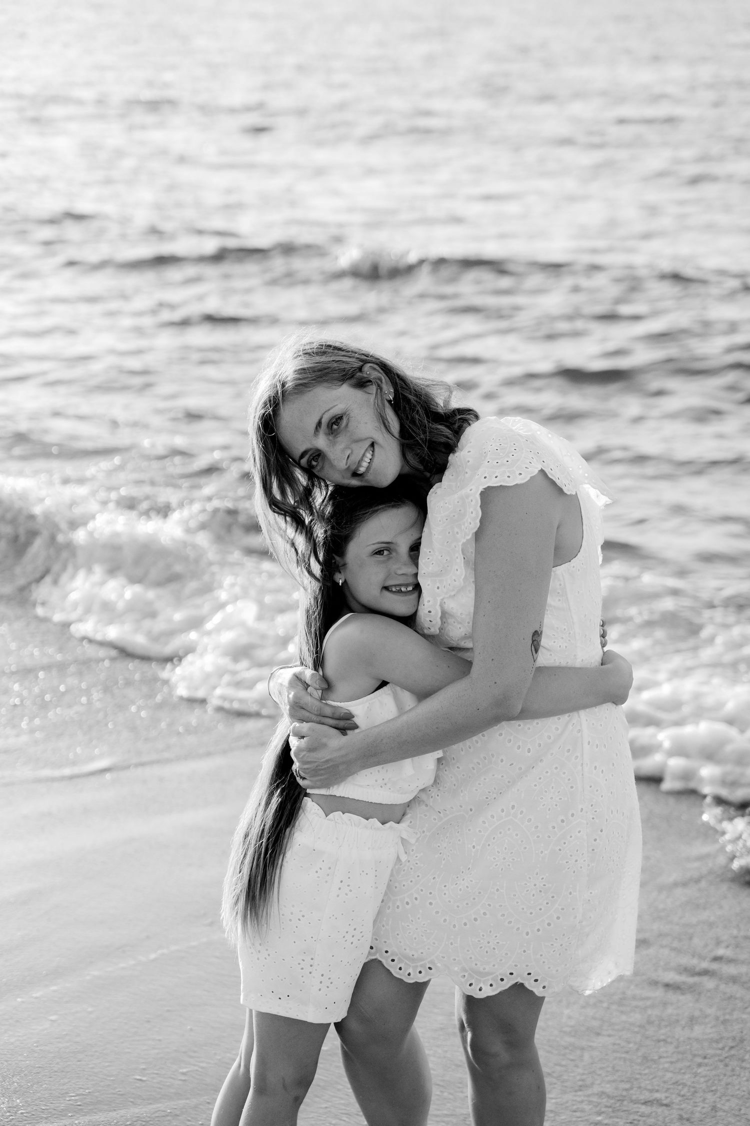 Black and white beach portrait showing tender embrace on sandy shore