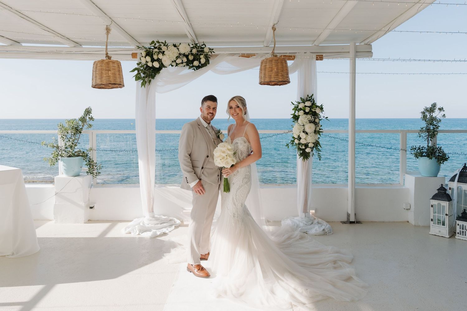 Elegant beach wedding ceremony setup with white decor and ocean views.