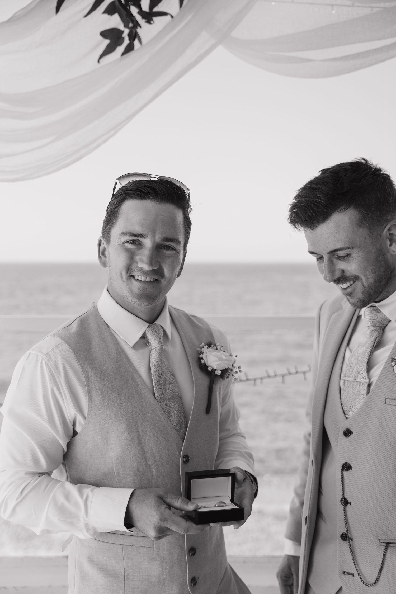 Wedding party members in light colored suits share a moment before the ceremony.