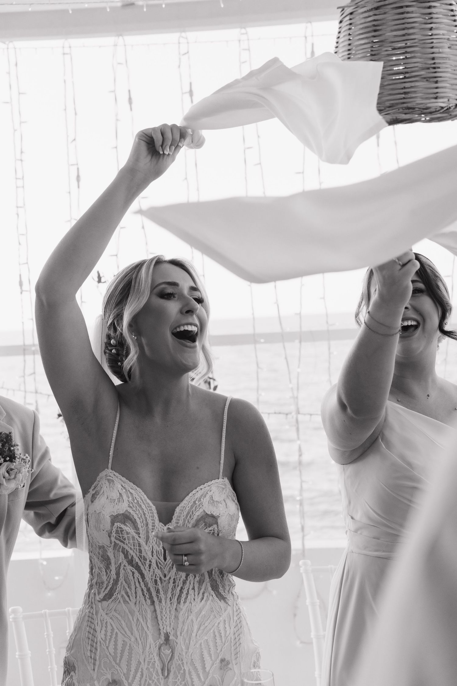 Bridesmaids in white dresses laugh and dance together during reception celebrations.