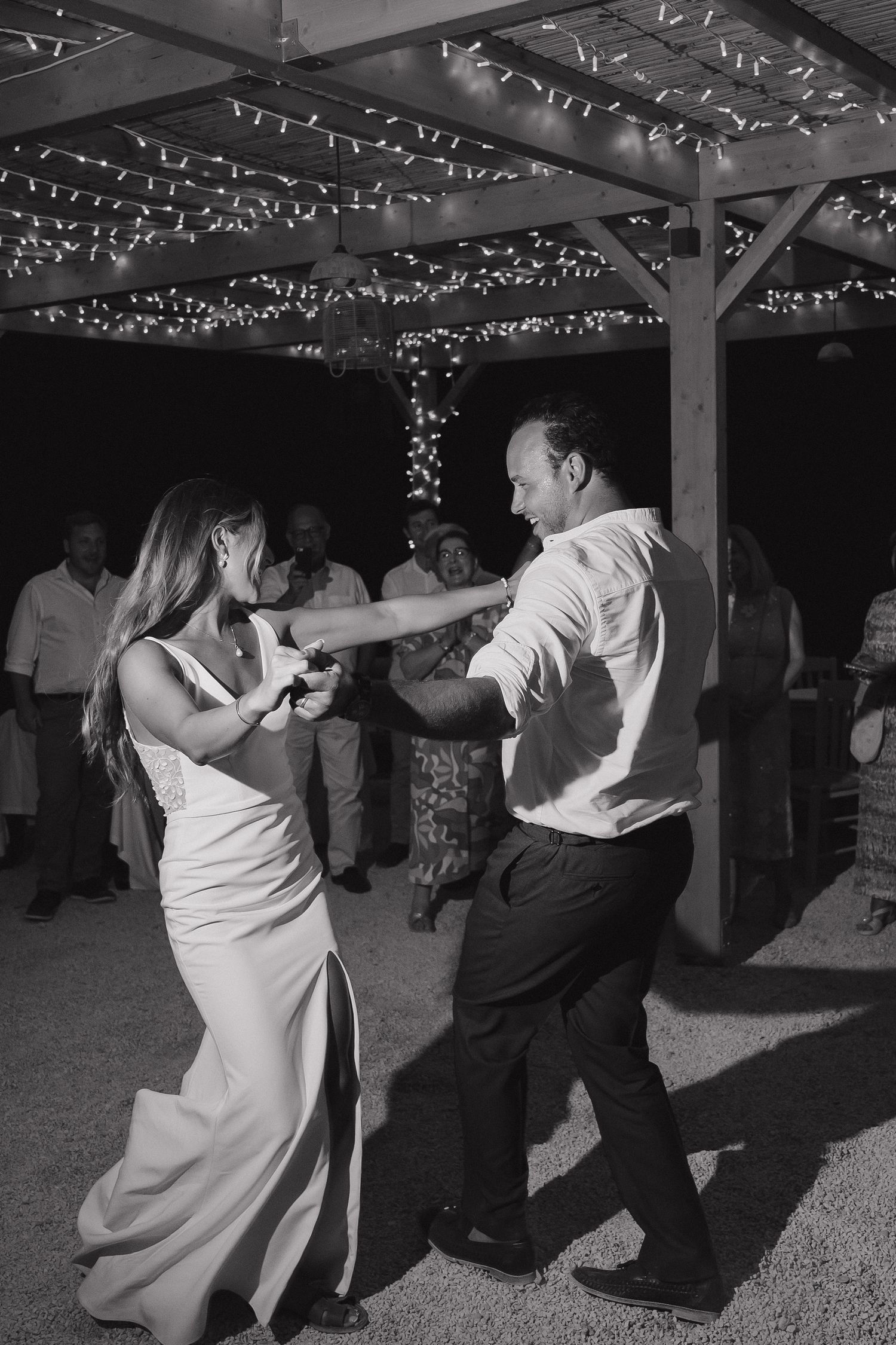 Couple dancing beneath fairy lights at outdoor evening reception.