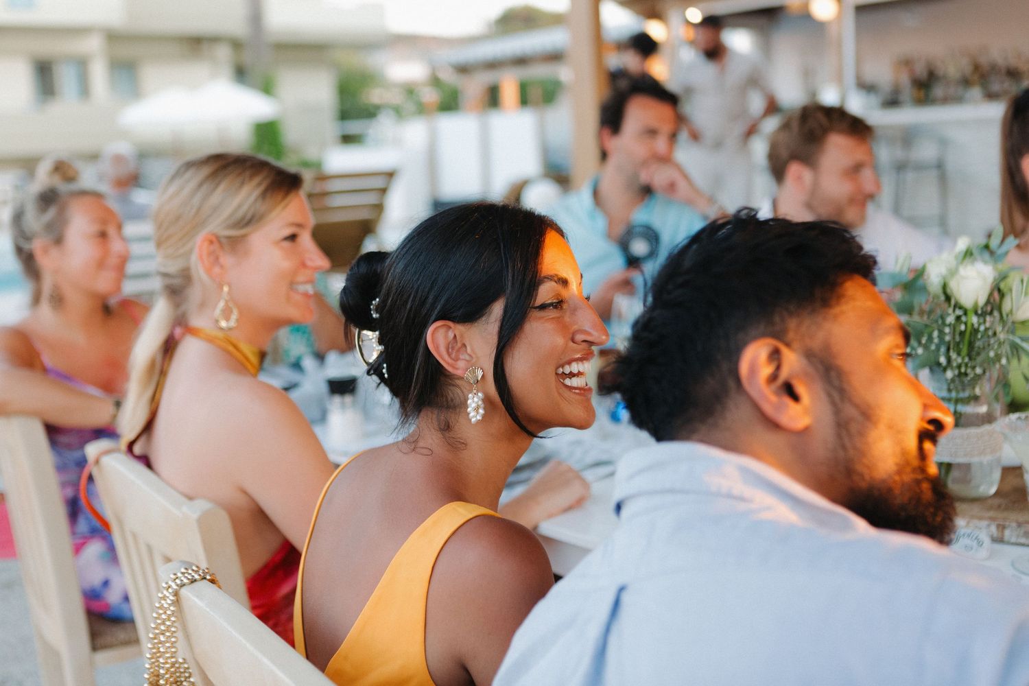 Wedding reception guests enjoying and laughing together at an outdoor celebration.