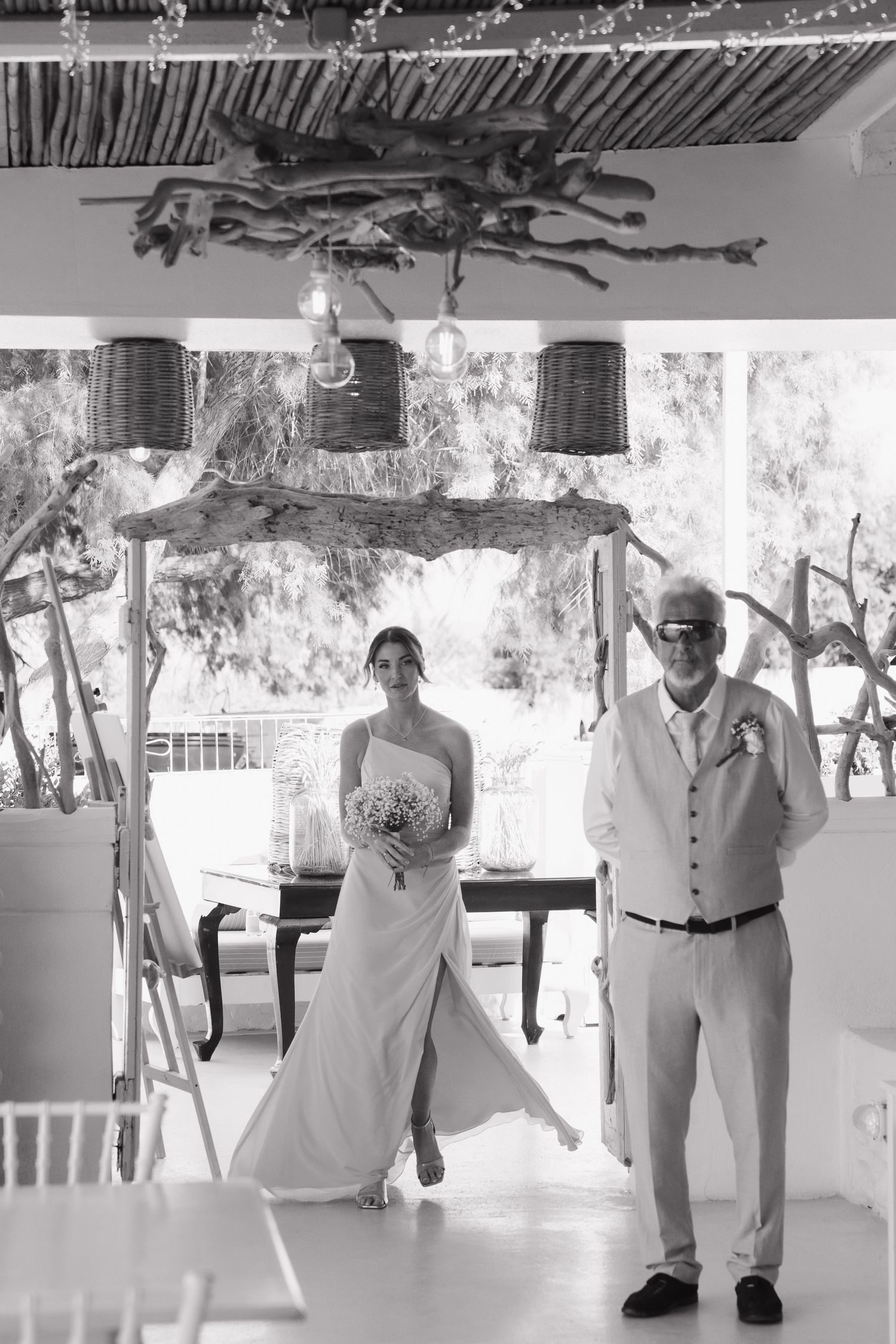 Black and white photo of two people during entrance procession at beach wedding ceremony.