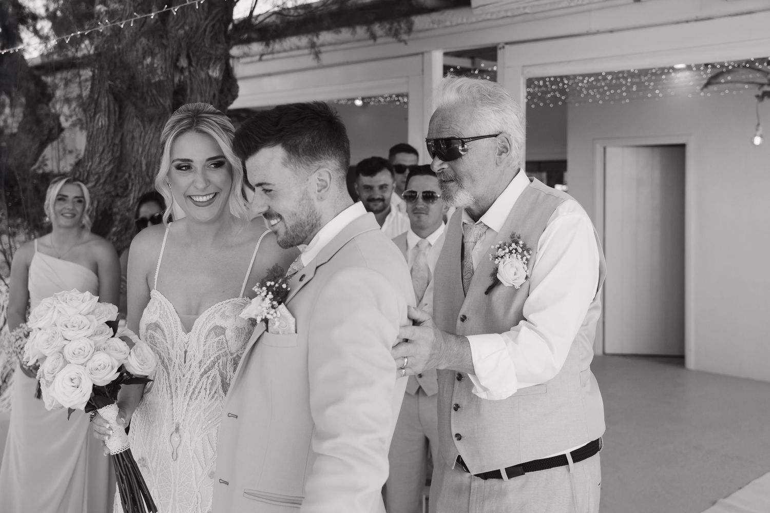 Black and white wedding ceremony photo with bridal party in light colored attire.