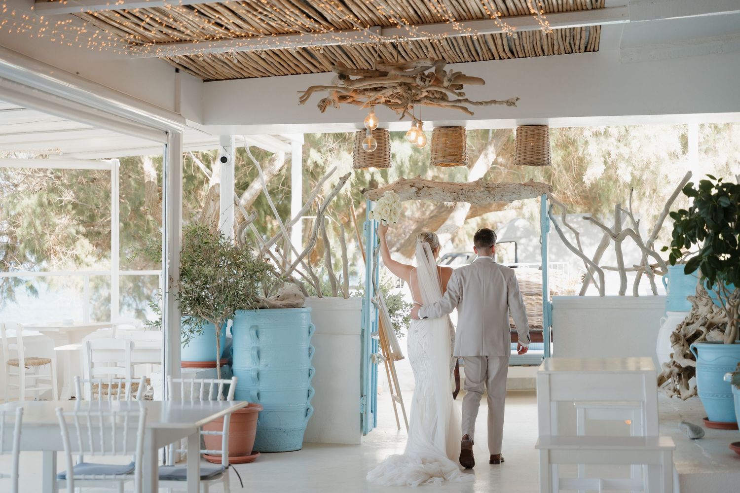 Couple walking through bright modern coastal wedding venue with bamboo ceiling.