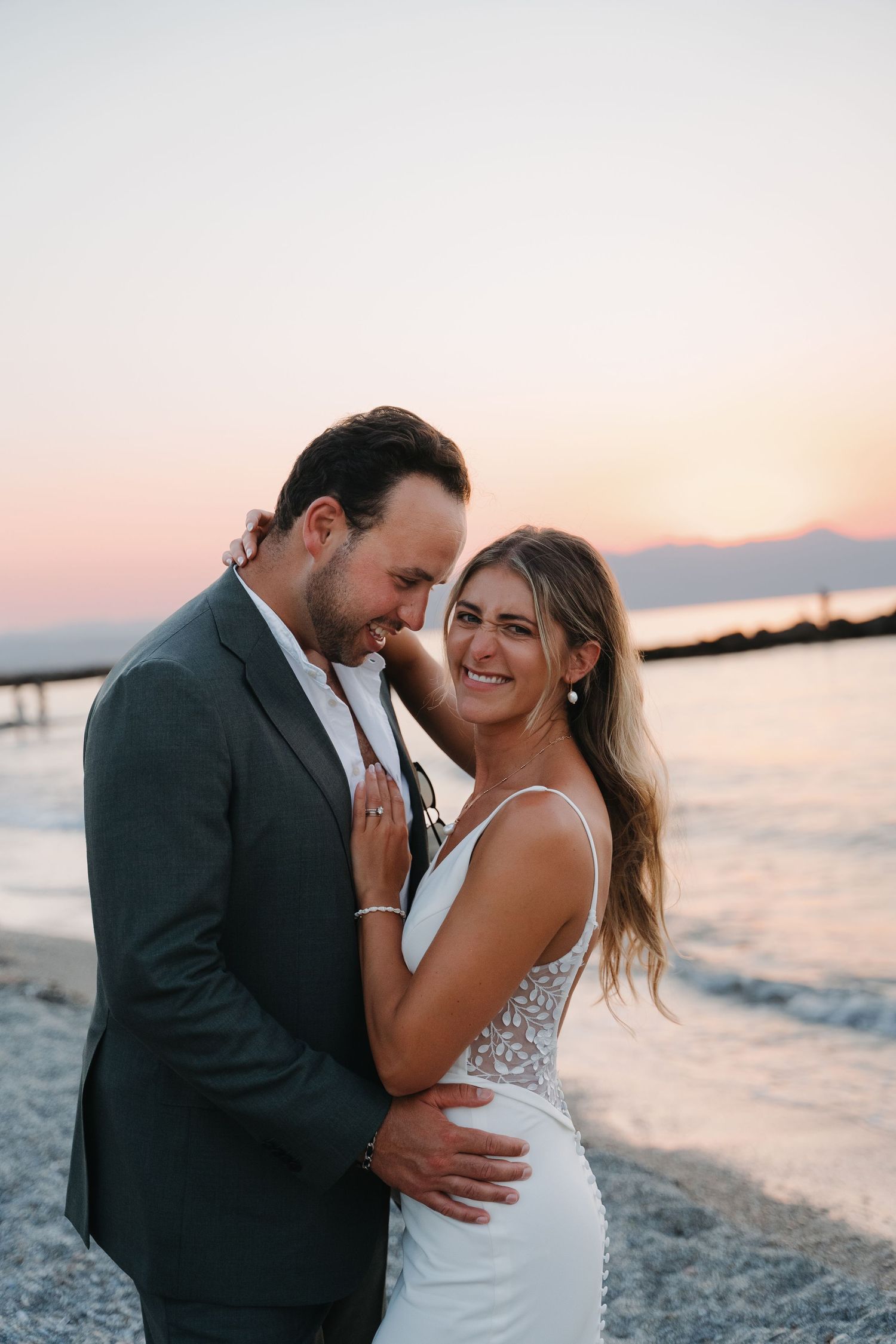 Bride and groom share intimate moment at sunset by the ocean during their wedding celebration.