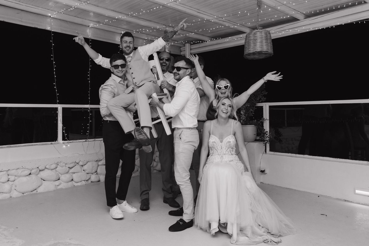 Black and white photo of wedding party having fun and celebrating on dance floor.