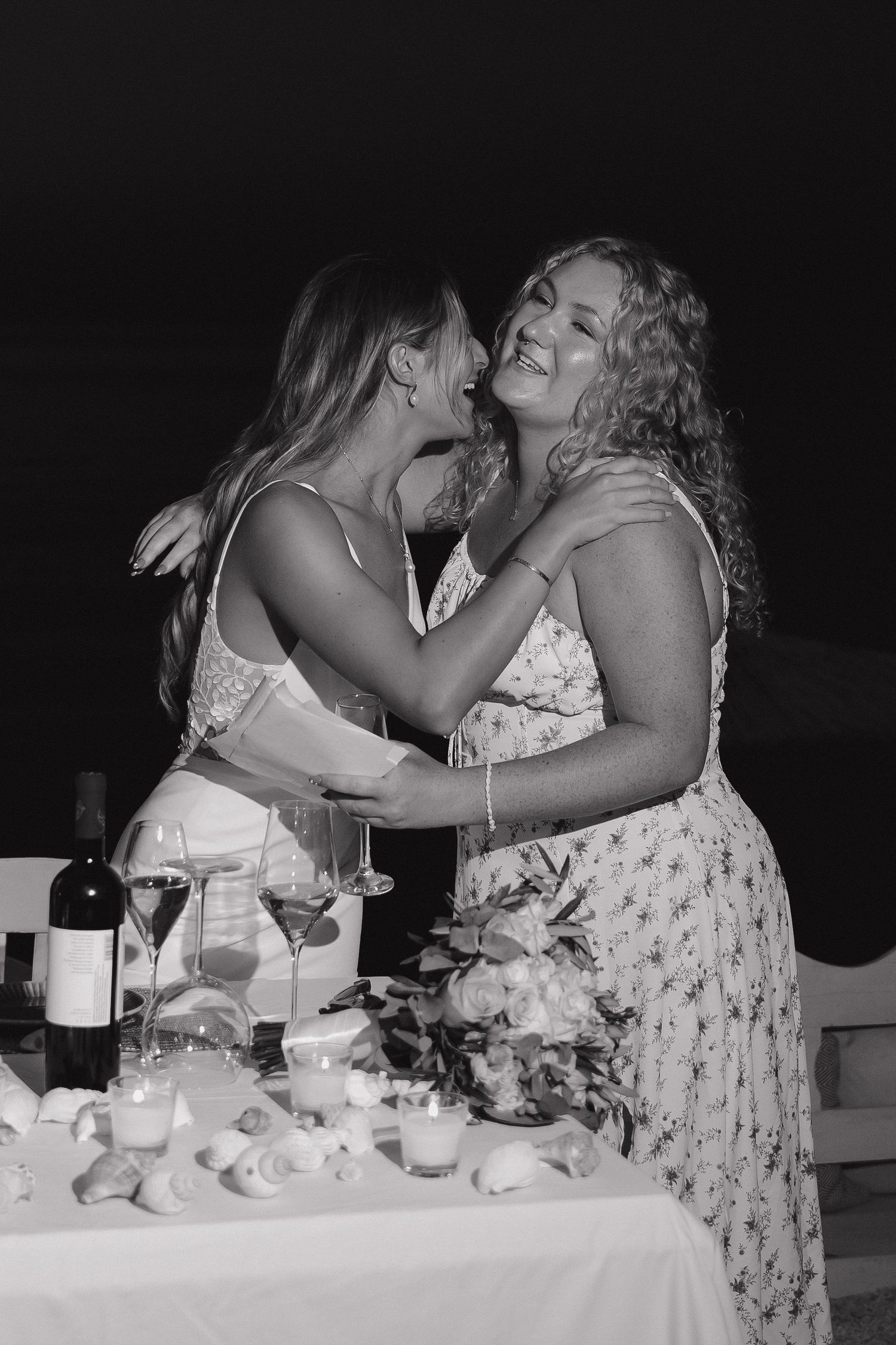 Candid black and white moment between two guests at an elegant wedding reception.