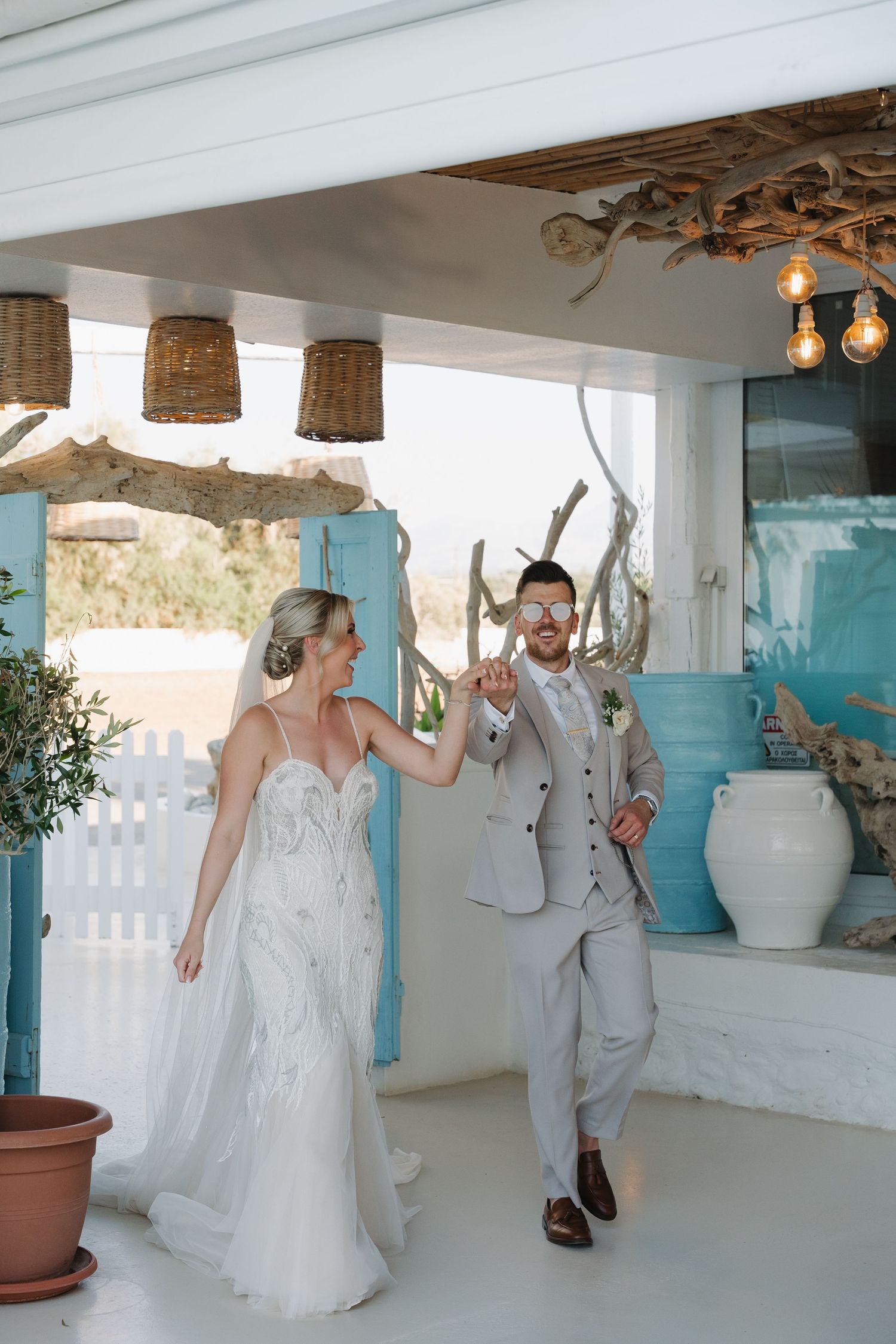 Joyful newlyweds dancing together in a Mediterranean-style venue with wicker pendant lights.