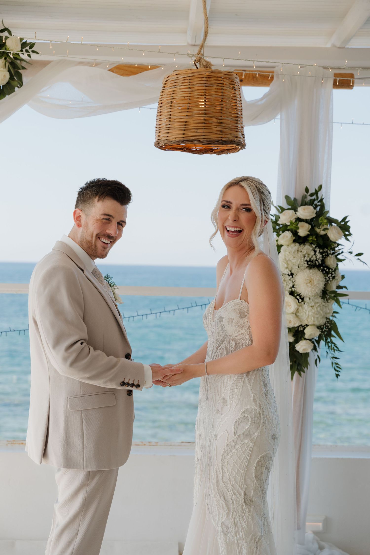 Wedding couple shares joyful moment at oceanfront ceremony location.