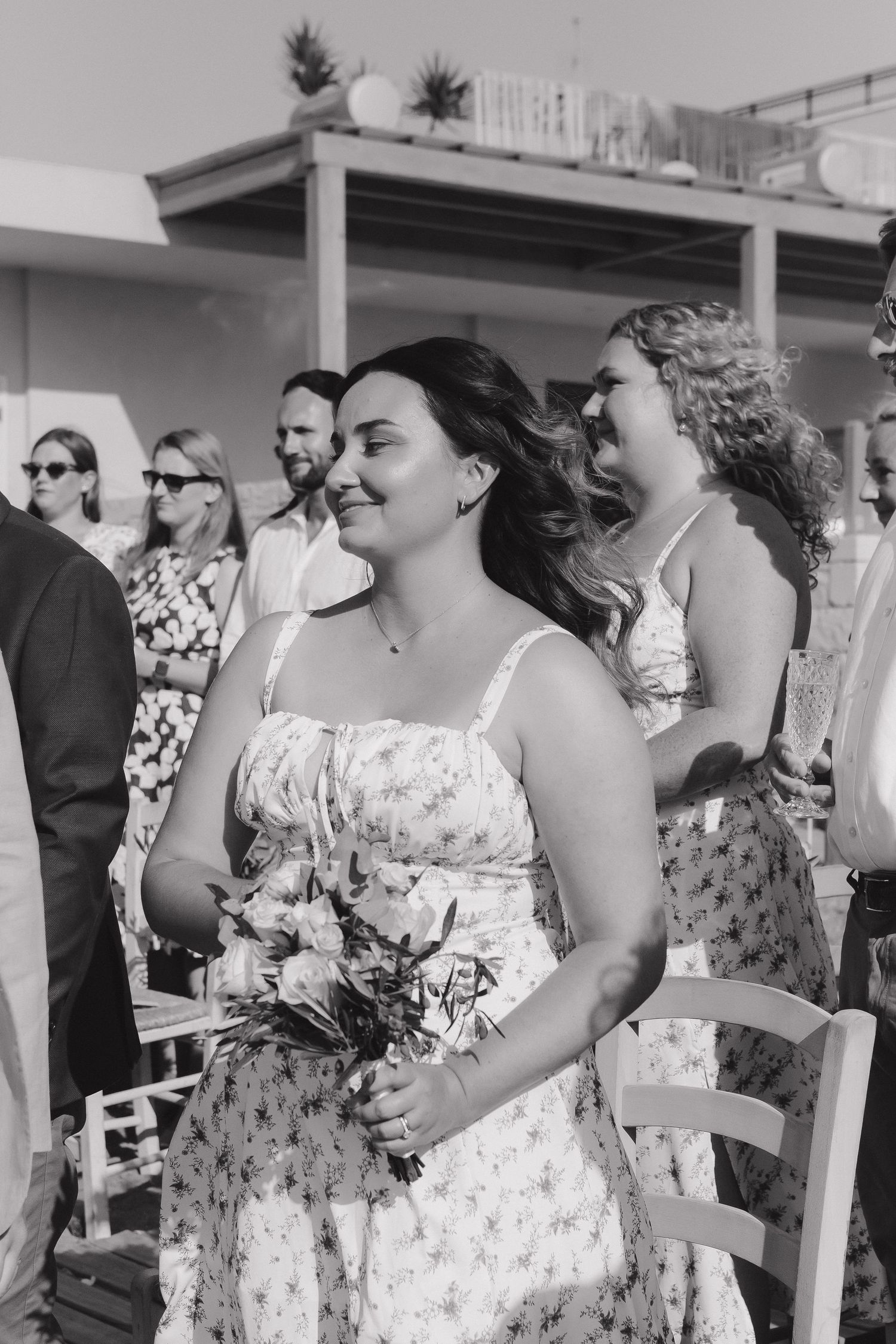 Attendees in summer dresses gather at an outdoor celebration in black and white.