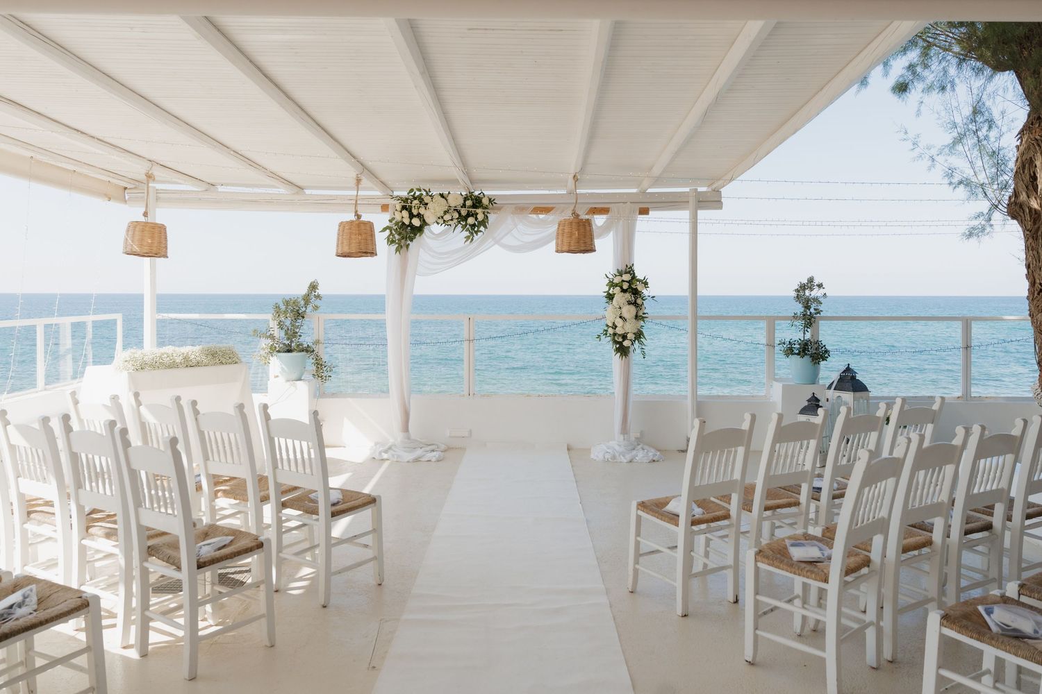 White coastal wedding ceremony venue with rows of chairs overlooking the ocean.