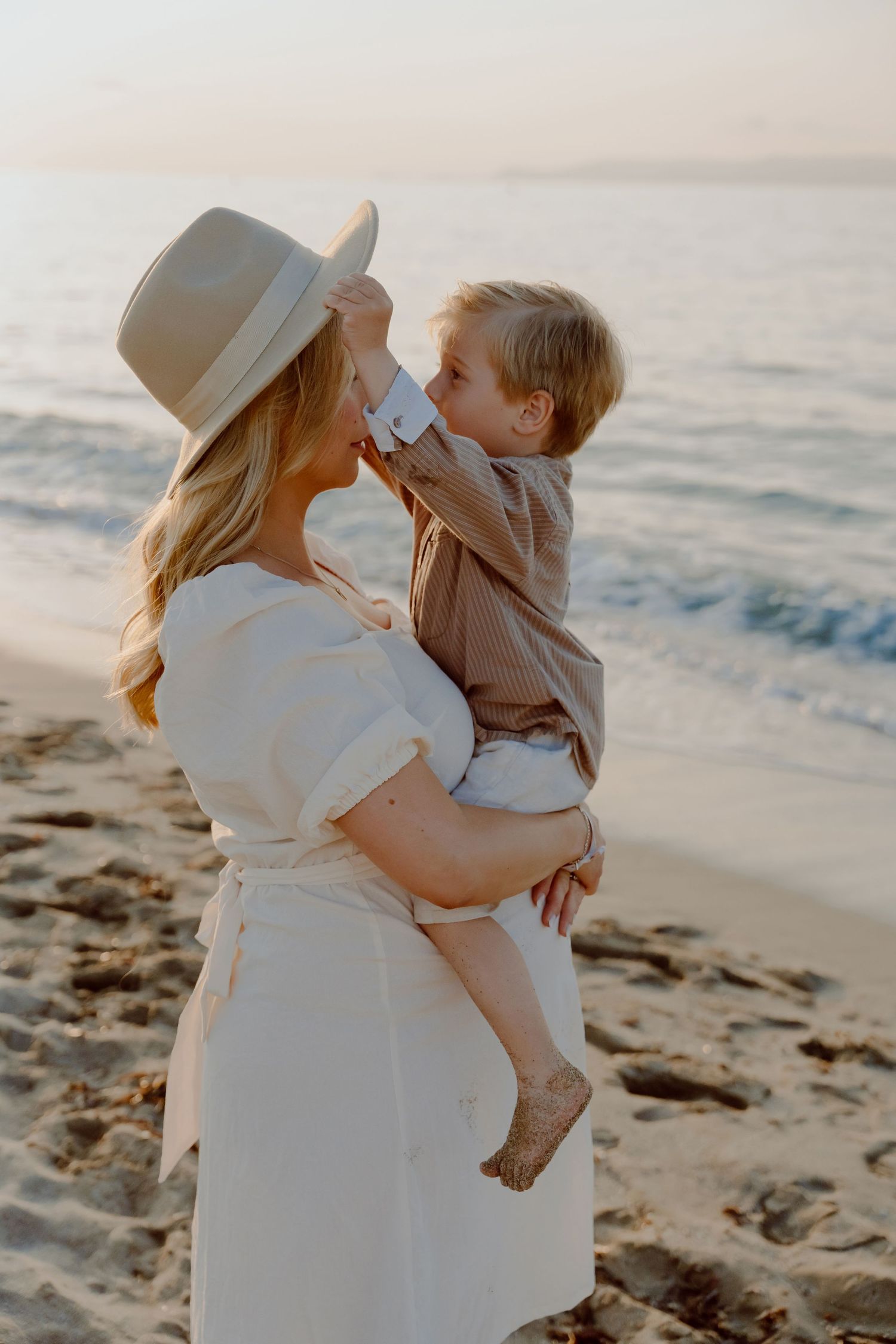 A tender moment shared between parent and child on a sandy beach at sunset.