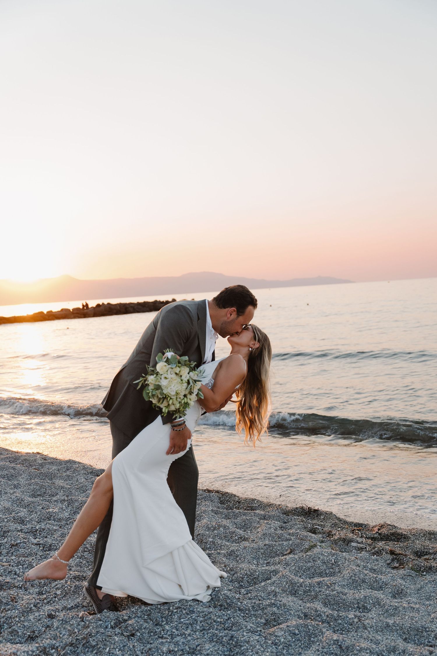 Romantic beach sunset wedding photo of a couple embracing during their seaside portrait session.