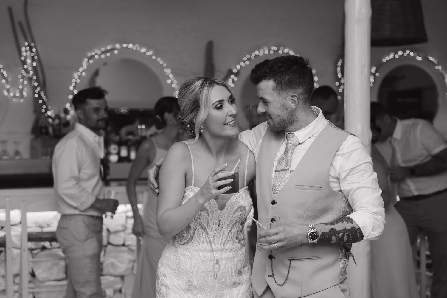 Black and white candid moment of couple sharing drinks at their reception.