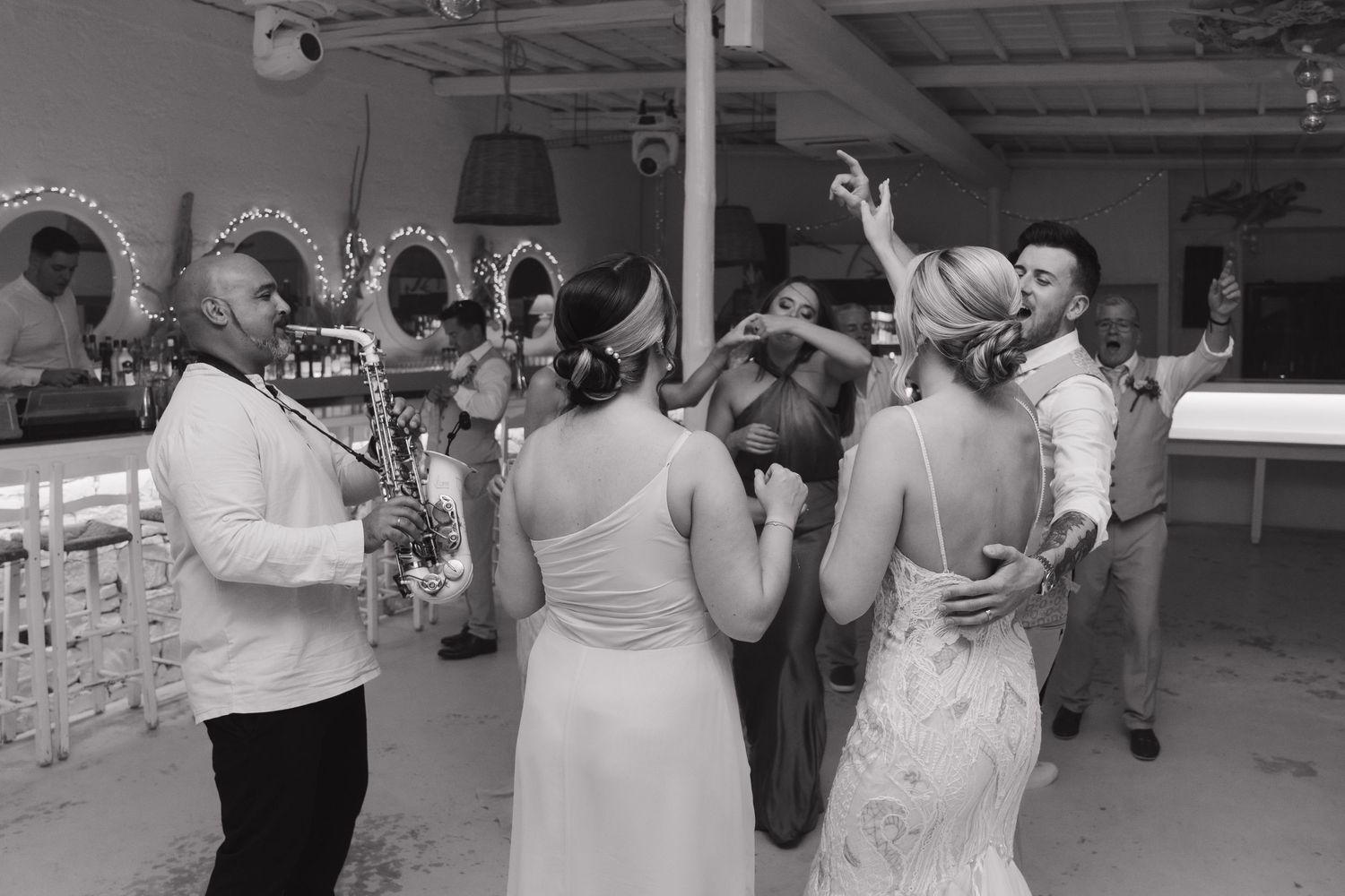 Black and white photo of wedding reception dance floor with guests celebrating.