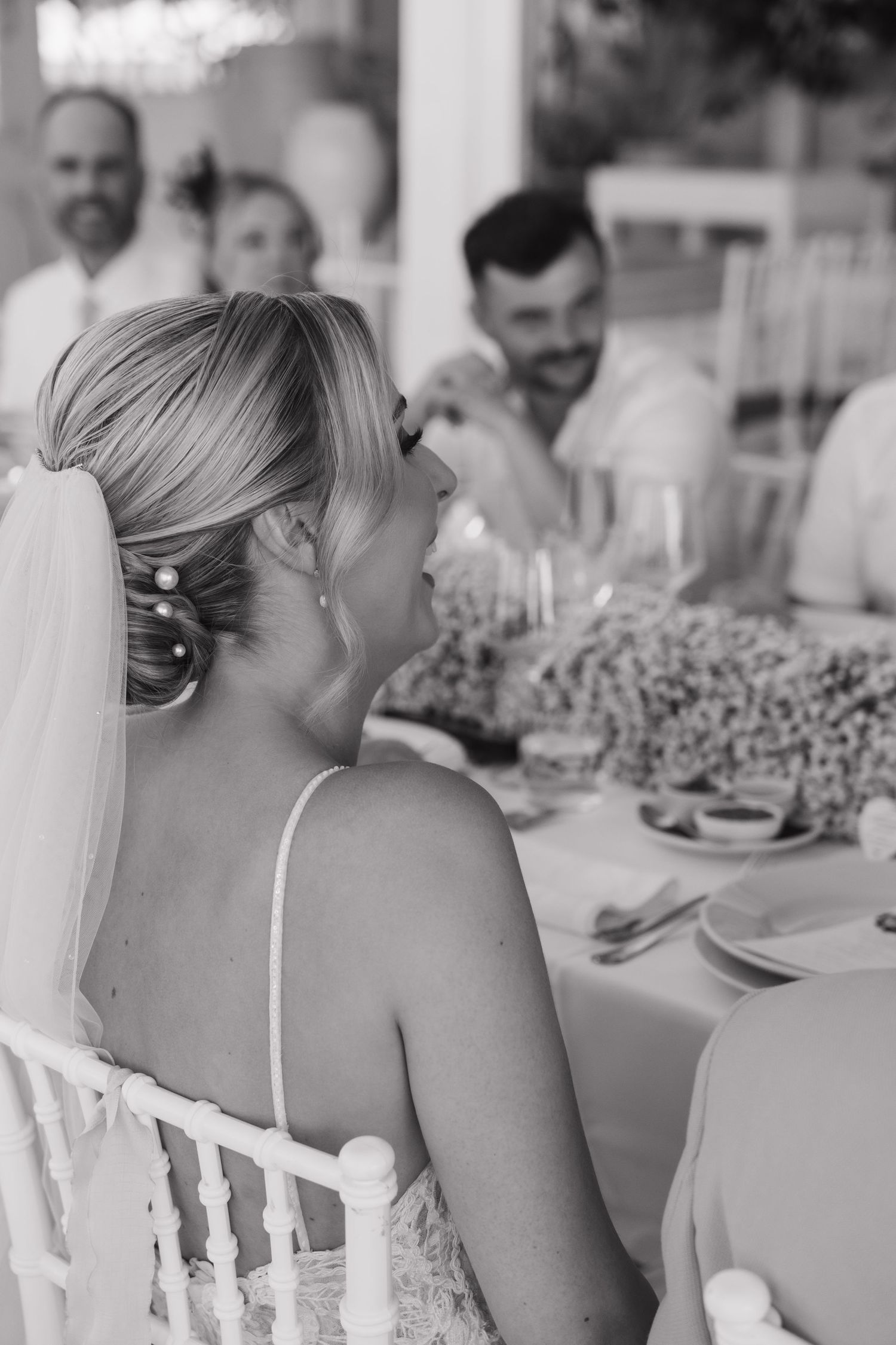 Black and white wedding reception photo showing guests enjoying dinner at decorated table.