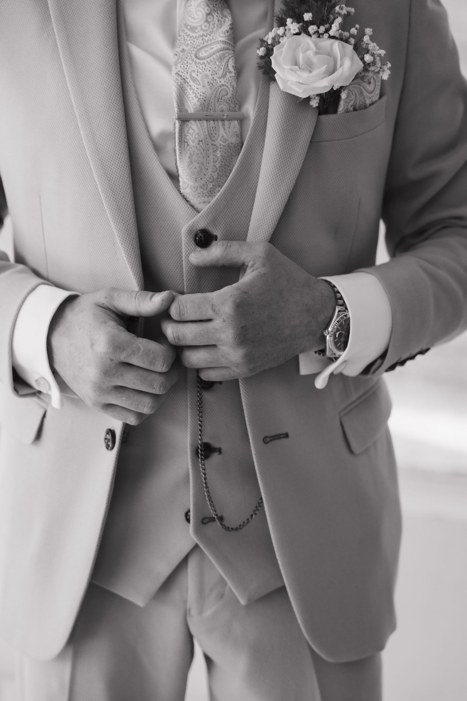 Close-up detail of formal attire showing boutonniere, tie and suit jacket.
