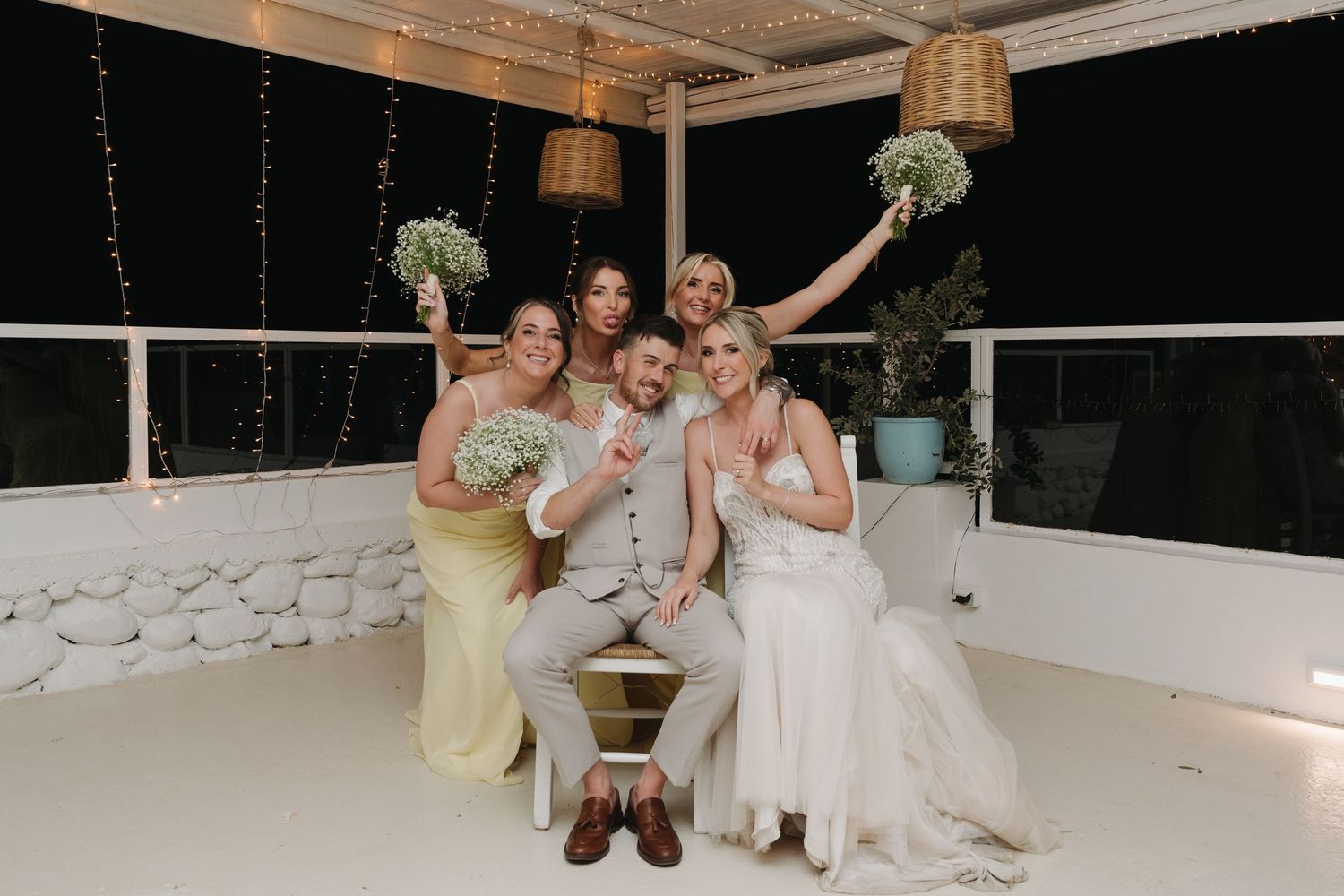 Fun group photo of bridesmaids and bride posing together on white dance floor.