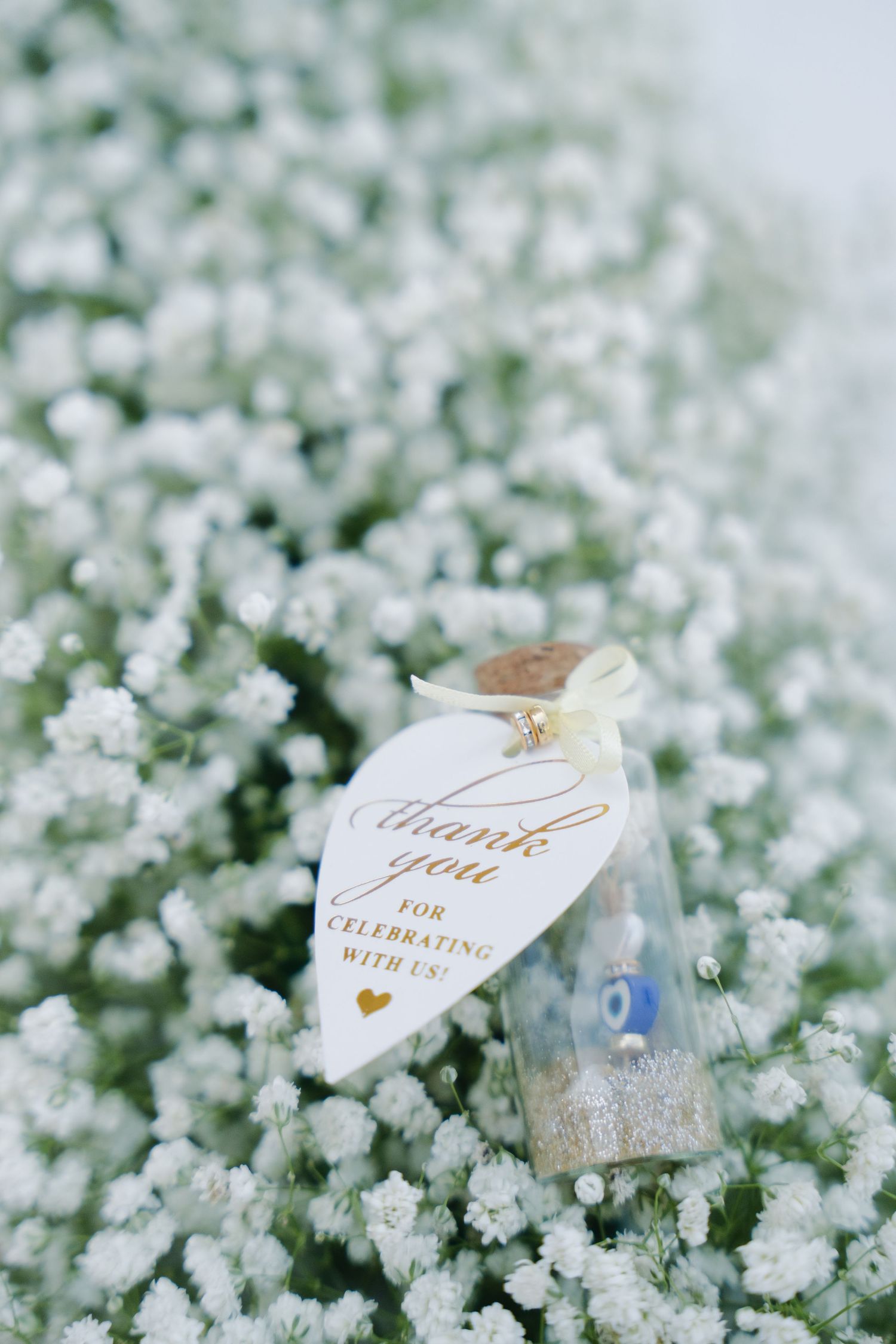White wedding favor tag nestled among delicate baby's breath flowers.