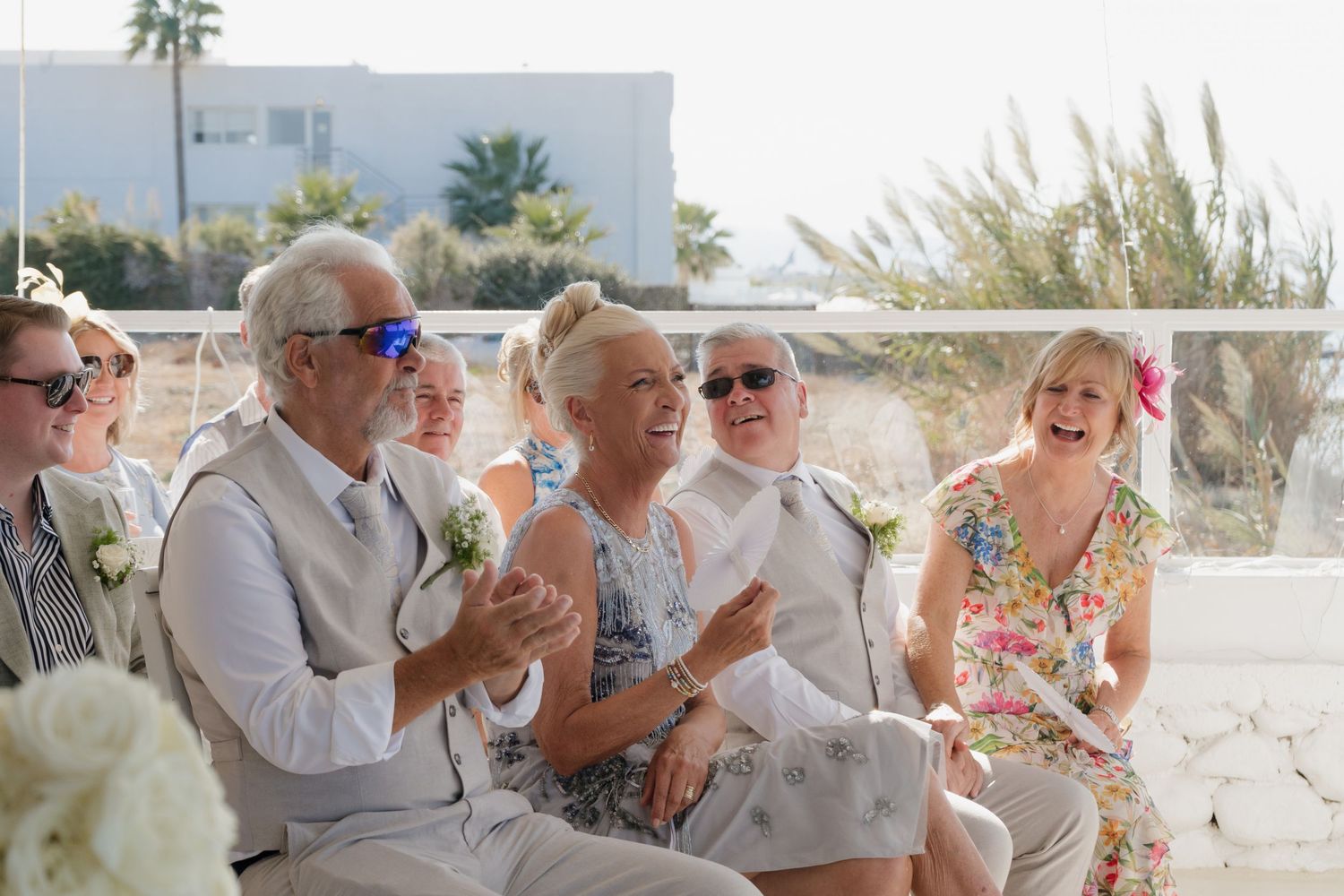 Wedding guests enjoying outdoor celebration in sunny beachside setting.
