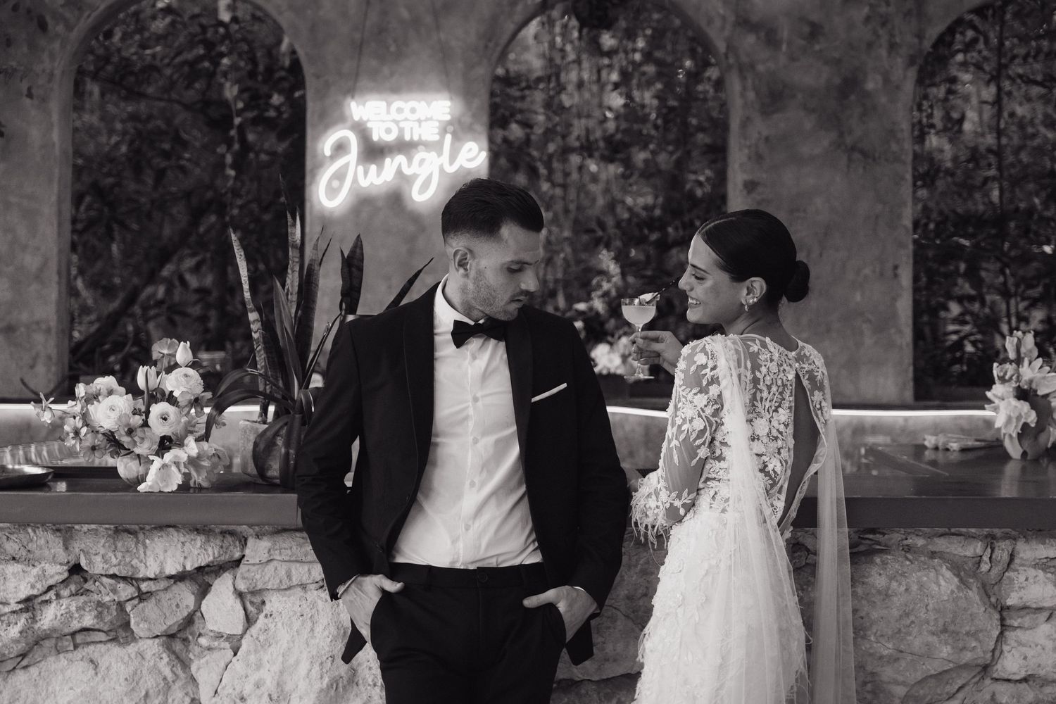 Elegant black and white wedding photo of a couple gazing at each other beneath stone archways.