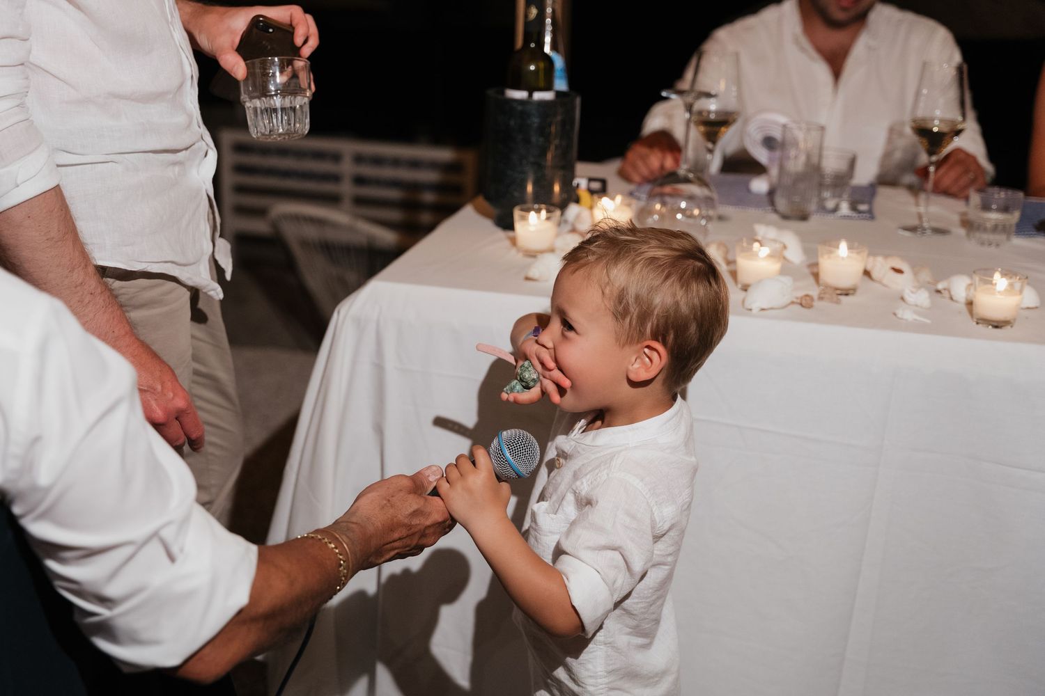 A candid moment at a wedding reception as a young boy eagerly reaches for dessert at a dining table.