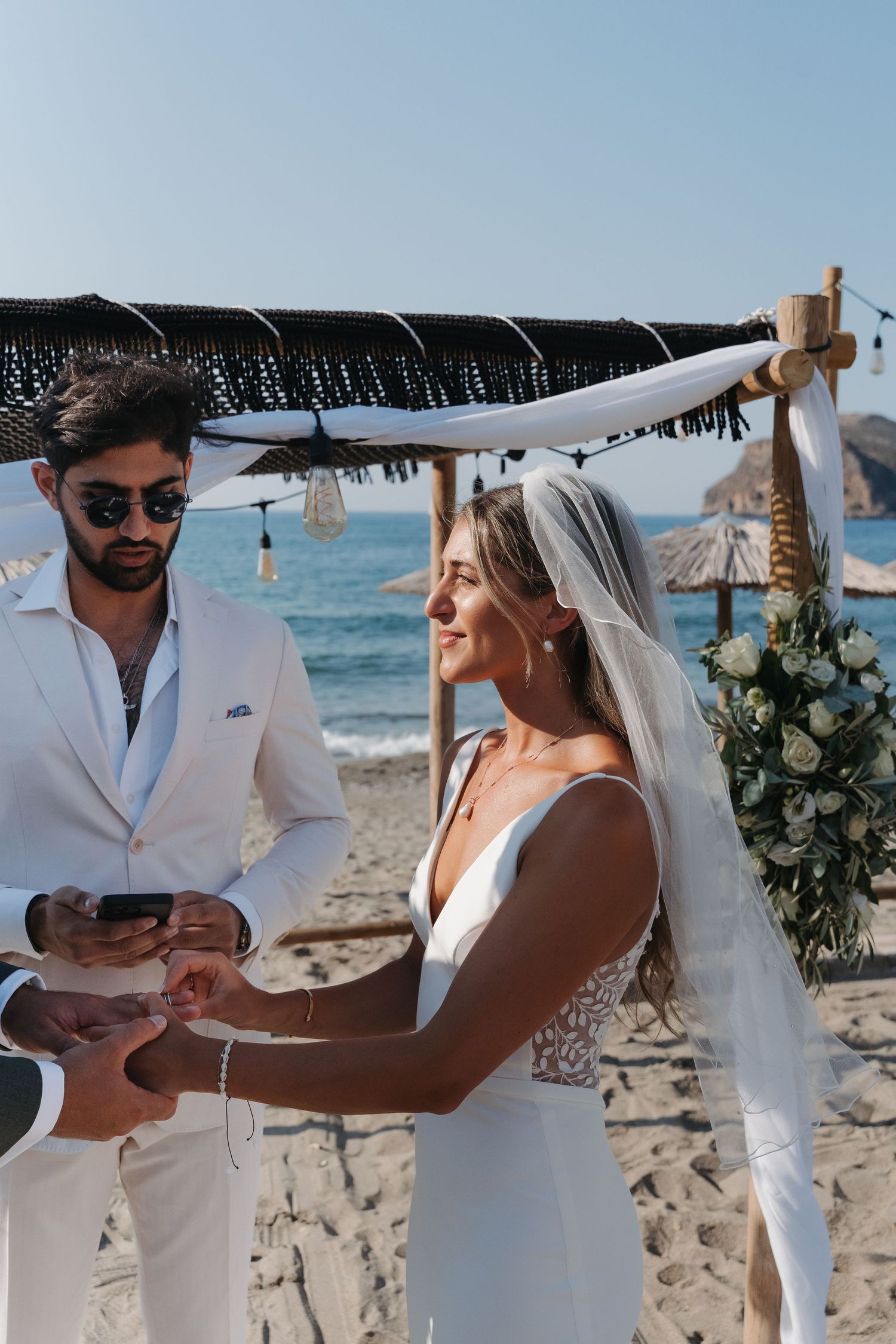 A romantic beach wedding ceremony under a bamboo canopy with ocean views.